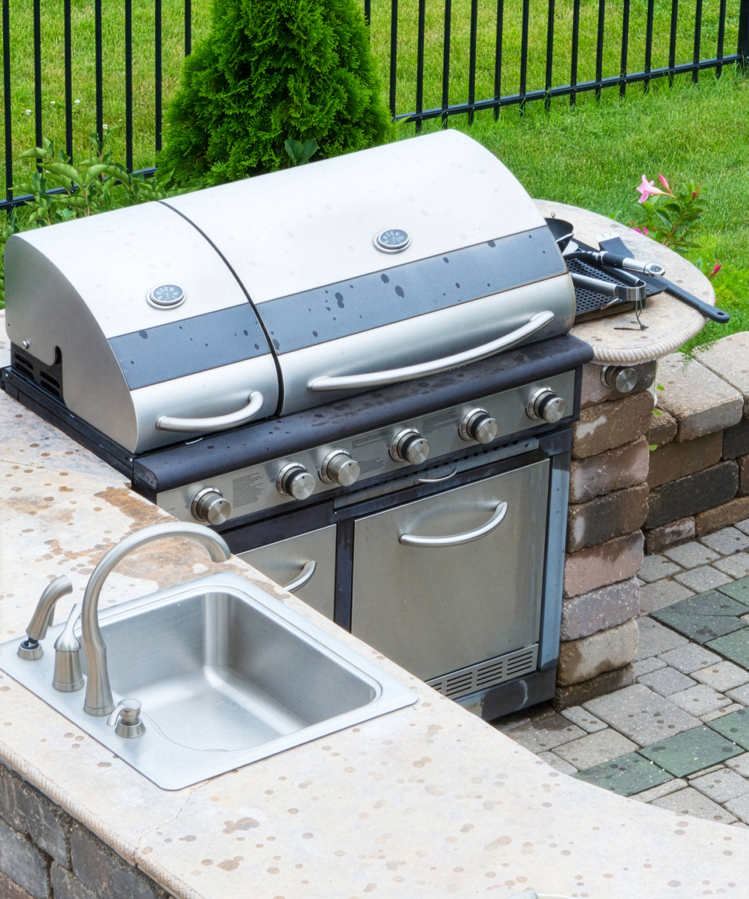 Edelstahlgrill und Waschbecken in einer Outdoorküche.