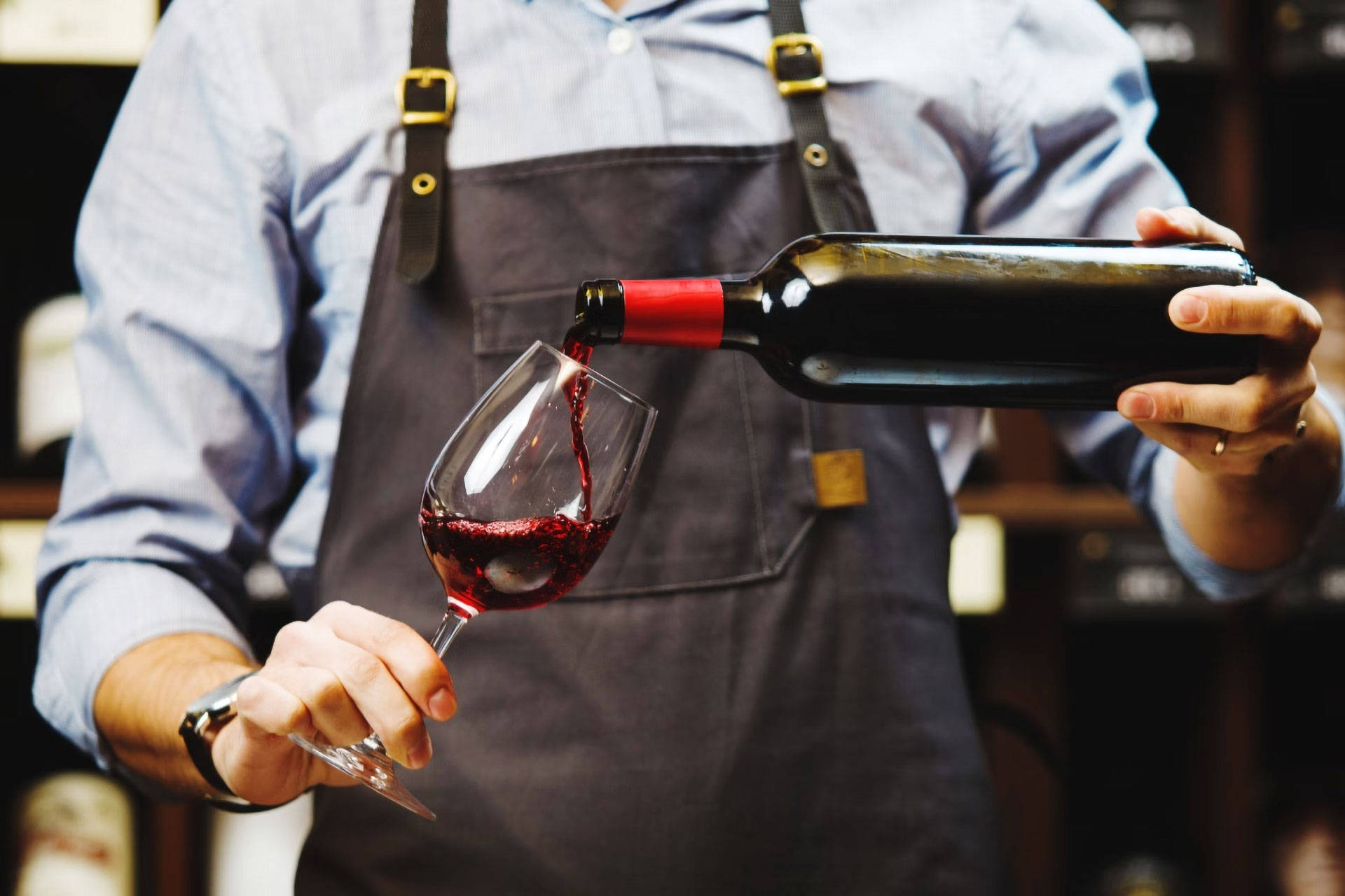 Ein Sommelier schenkt sich ein Glas Rotwein ein.