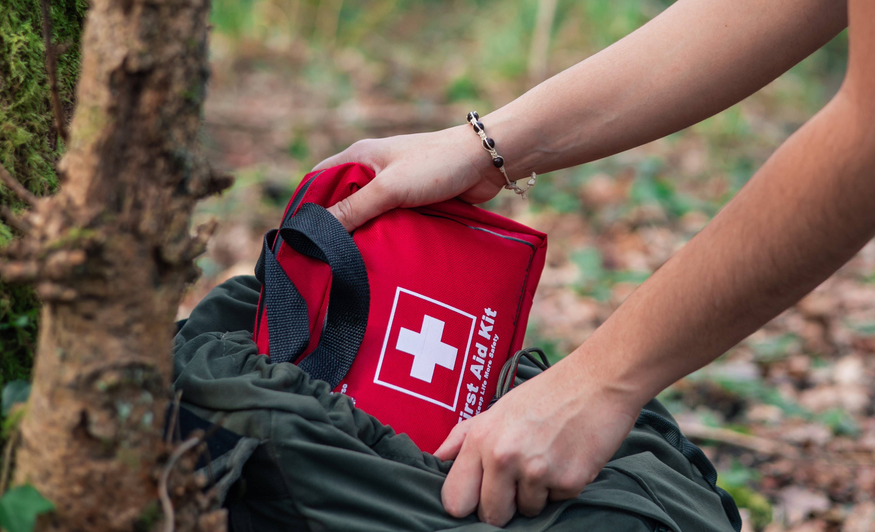 Eine Person packt draußen ein Erste-Hilfe-Set in ihre Tasche.