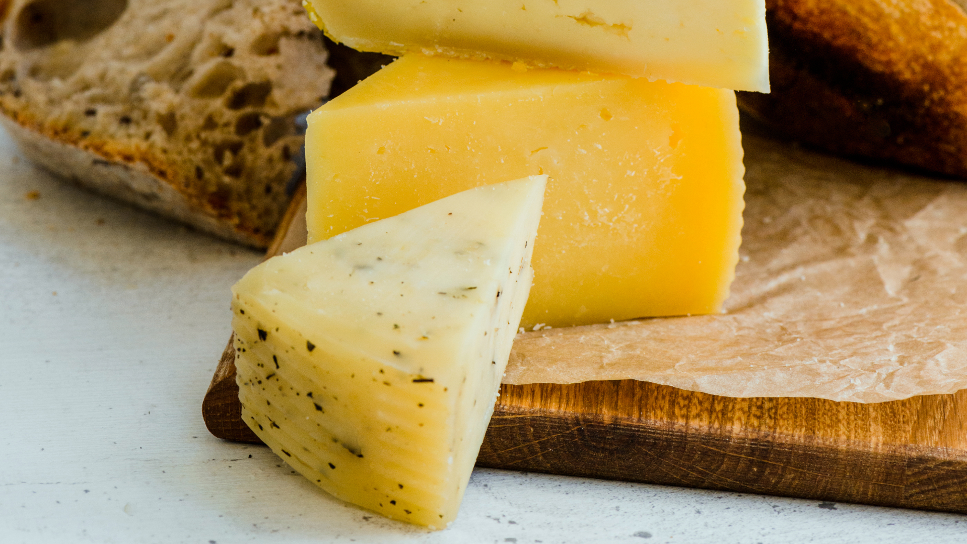 Verschiedene Käsestücke und Brot auf einem Holzbrett.