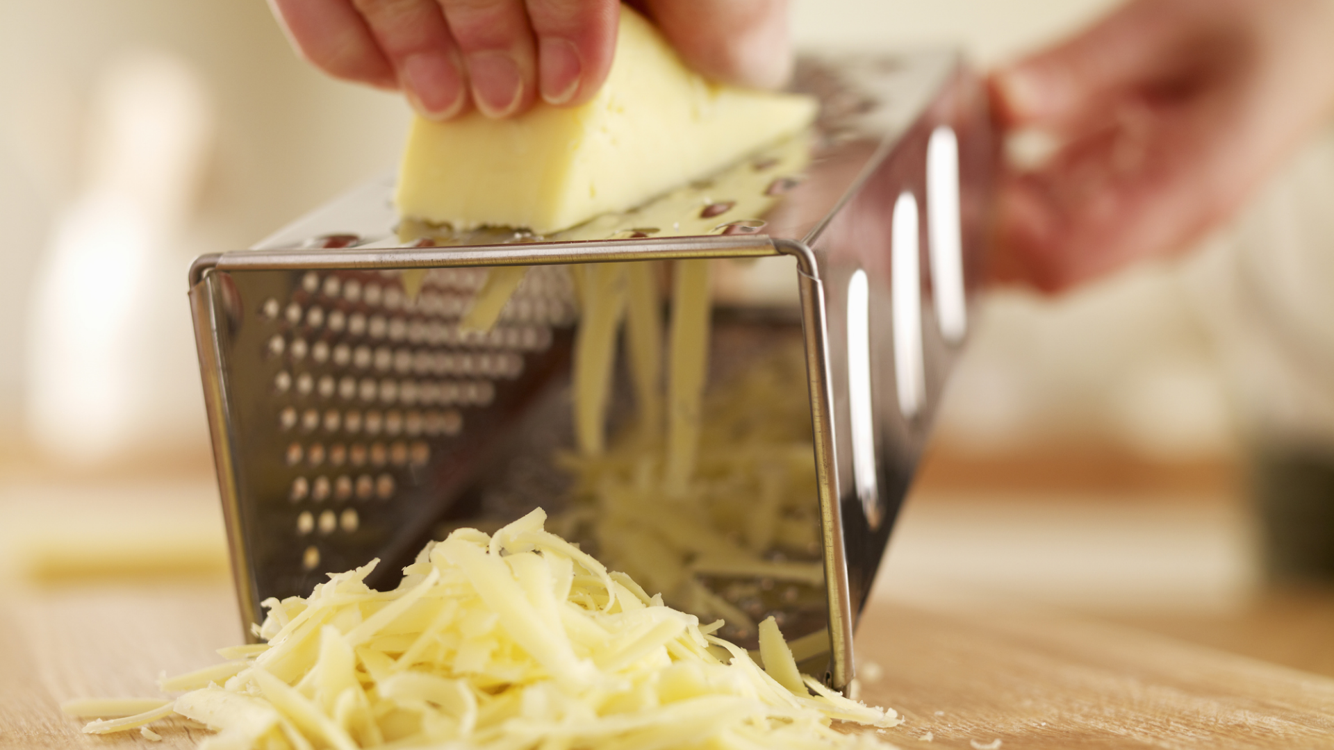 Reibeisen mit Käse über einem Schneidebrett.