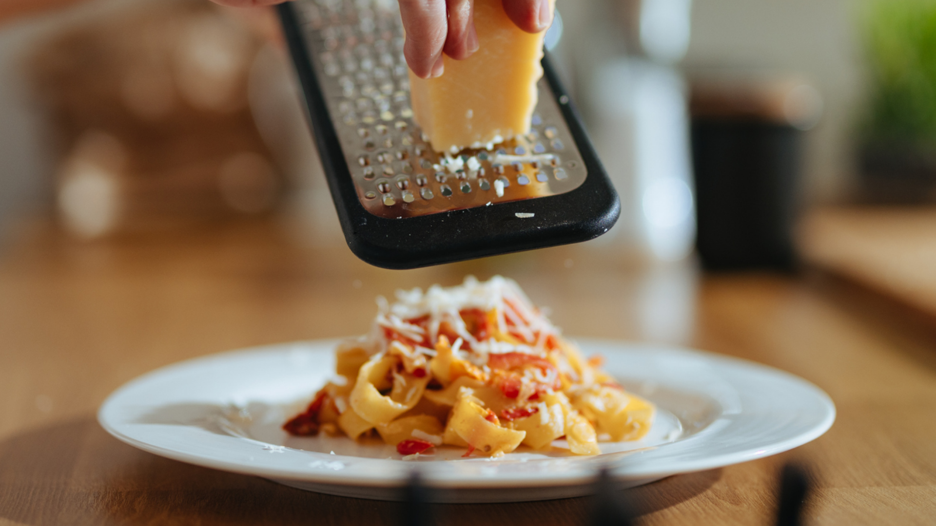 Reibekäse wird über Pasta gerieben.