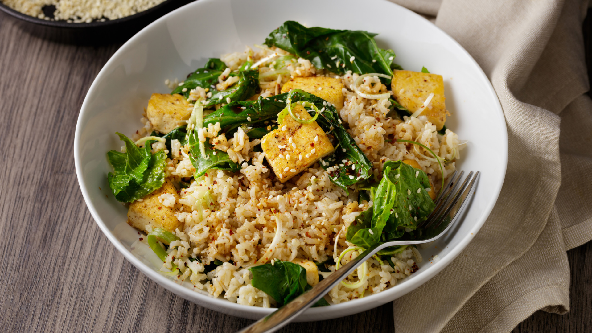 Reisgericht mit Tofu, grünem Gemüse und Sesamsamen.