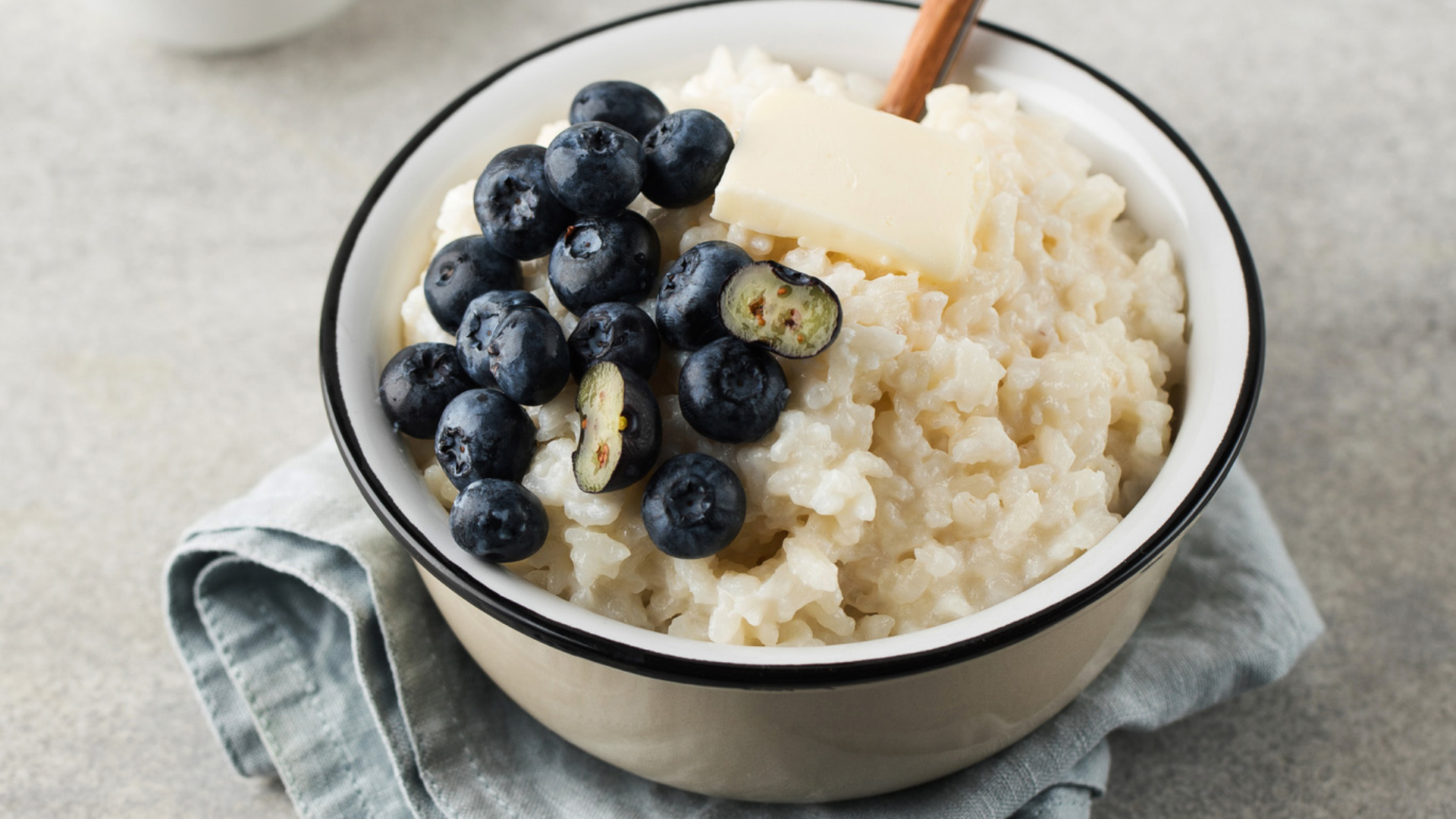 Milchreis mit Blaubeeren und Butter in einer Schüssel.