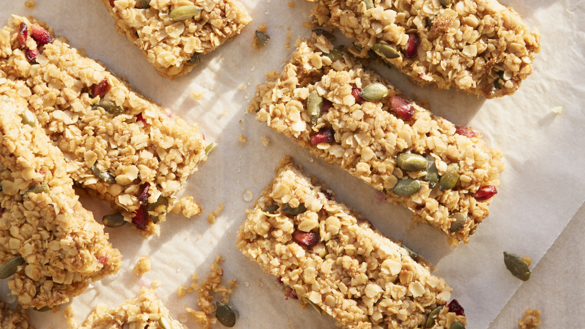 Müsliriegel mit Haferflocken, Kürbiskernen und Granatapfelkernen auf Papier.