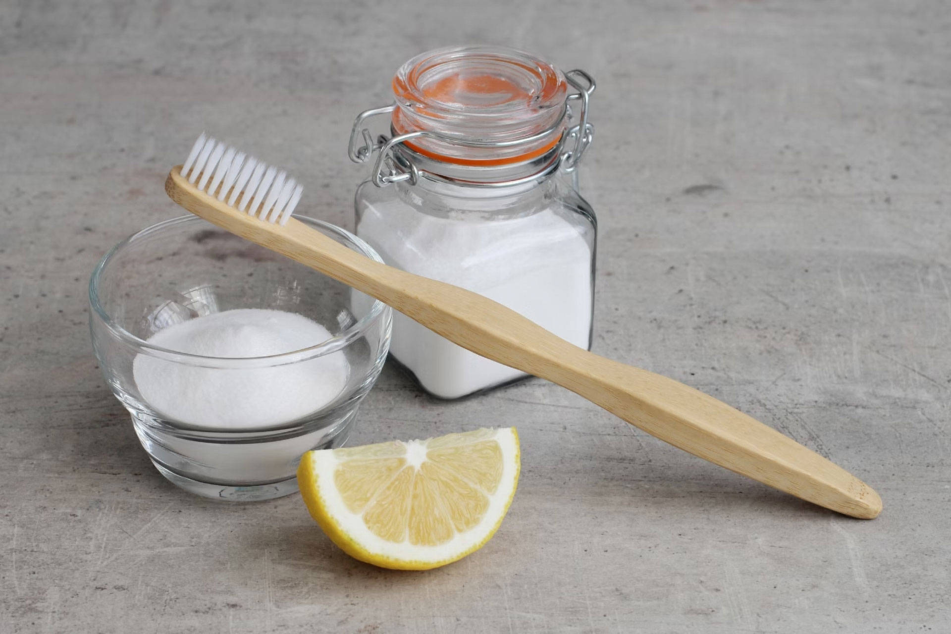 Zitrone, Salz, Backpulver und eine Zahnbürste liegen bereit, um Flecken zu entfernen.