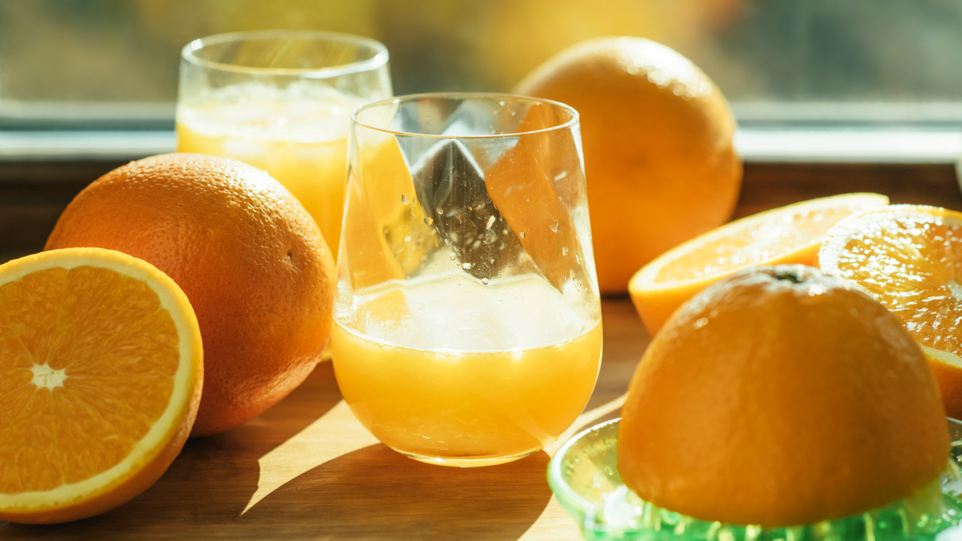 Zwei Gläser Orangensaft mit Orangen und Saftpresse.