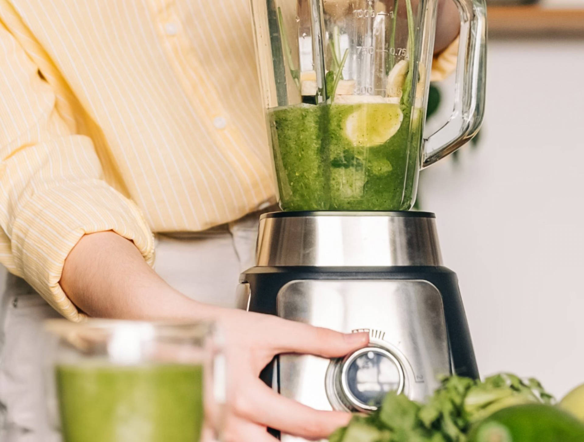 Eine Frau mixt einen grünen Saft mit Limette und Spinat
