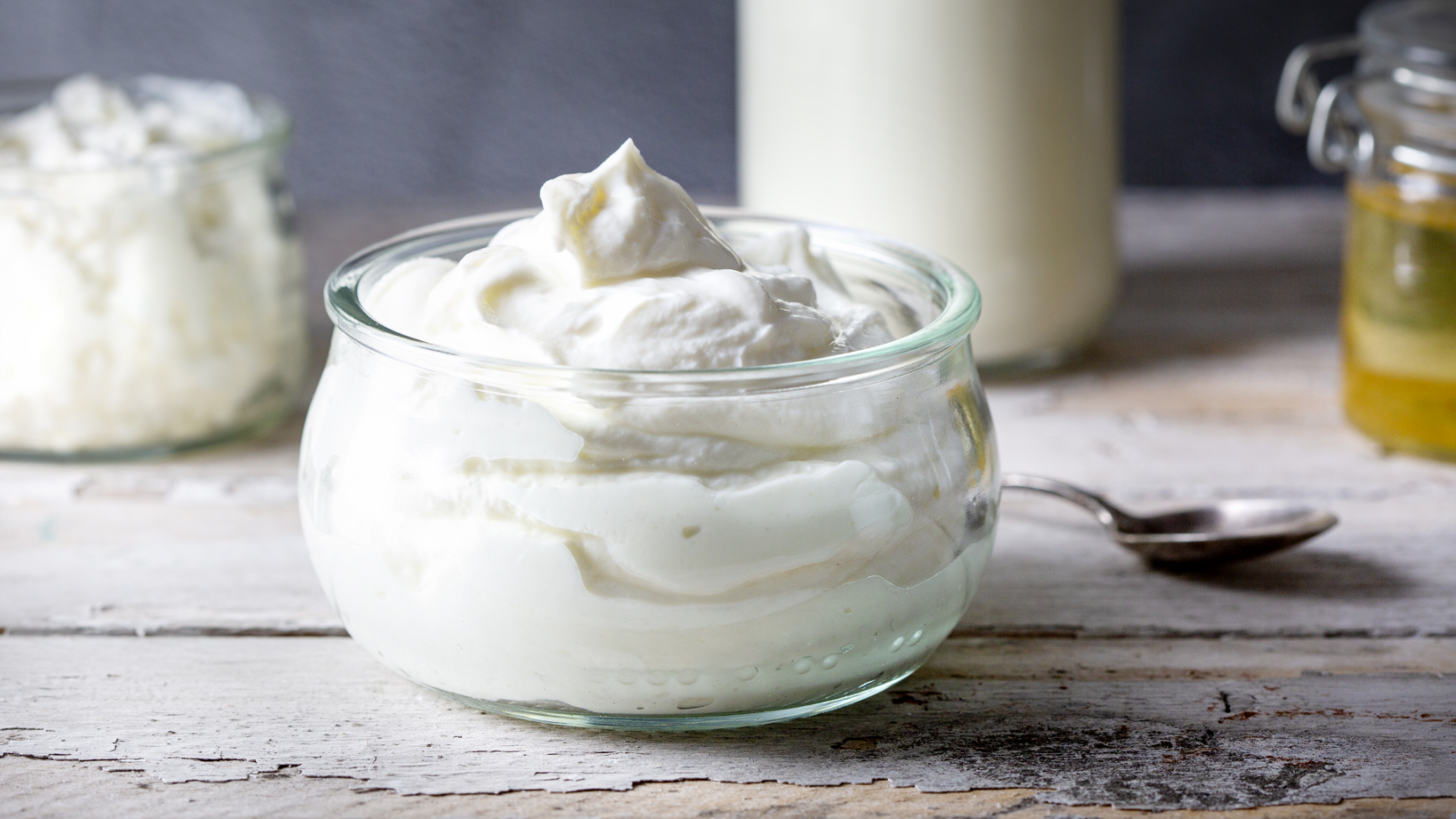 Weißer cremiger Schmand in Glas auf Holztisch.