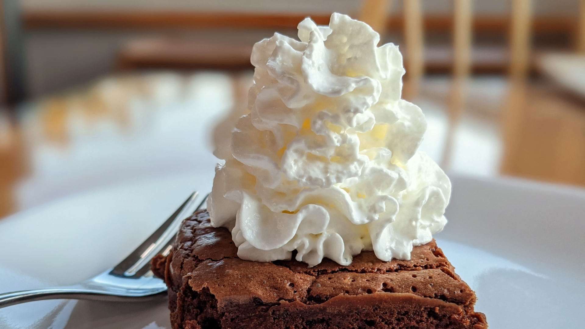 Schokoladenbrownie mit Schlagsahne auf Teller.