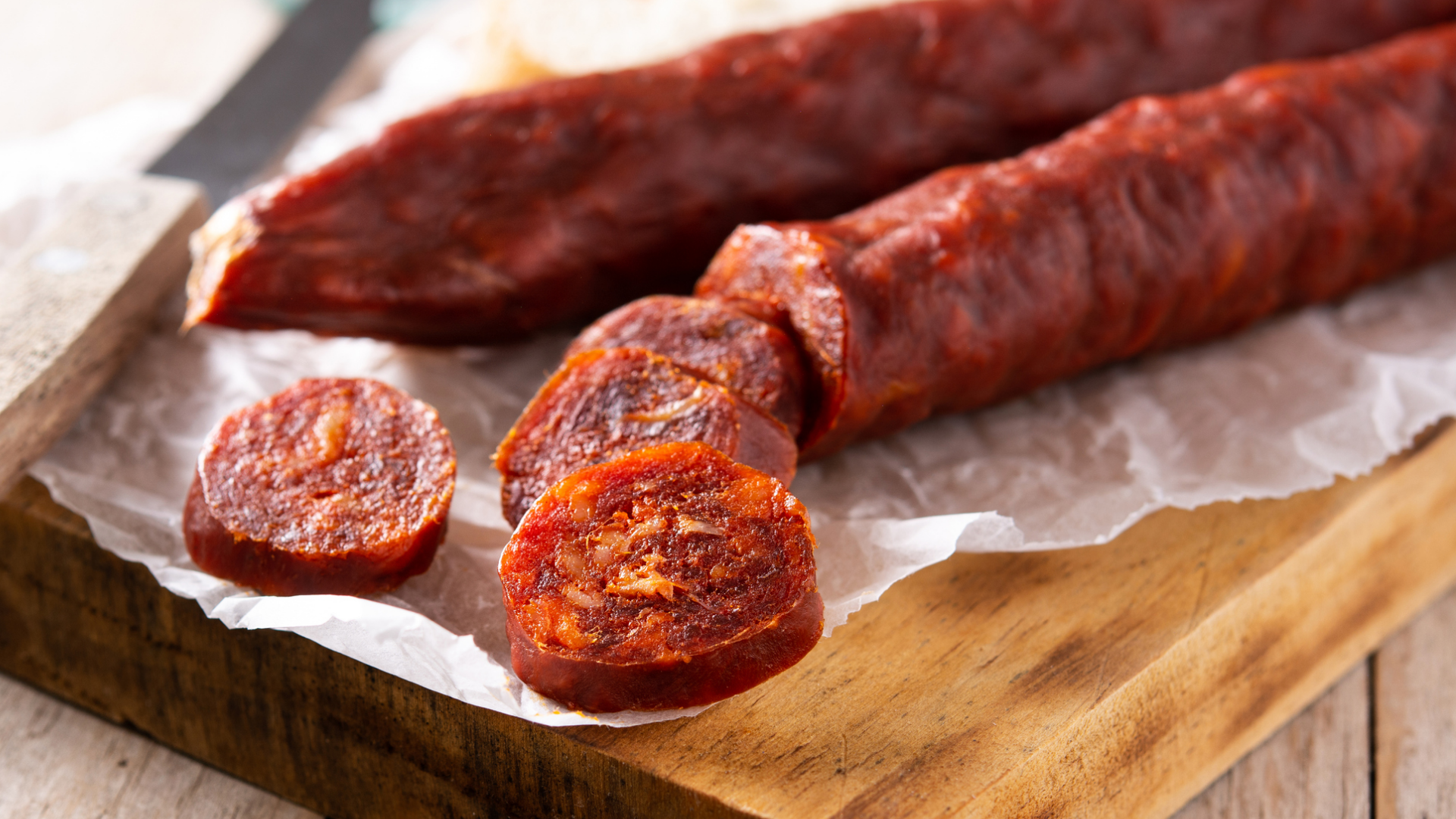 Rote Salami in Scheiben auf Holzbrett.