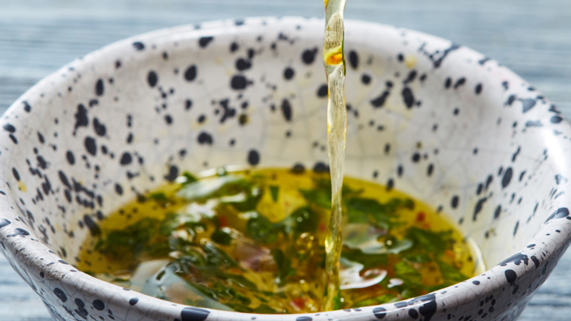 Goldgelbes Öl wird in grüne Kräutersauce gegossen.