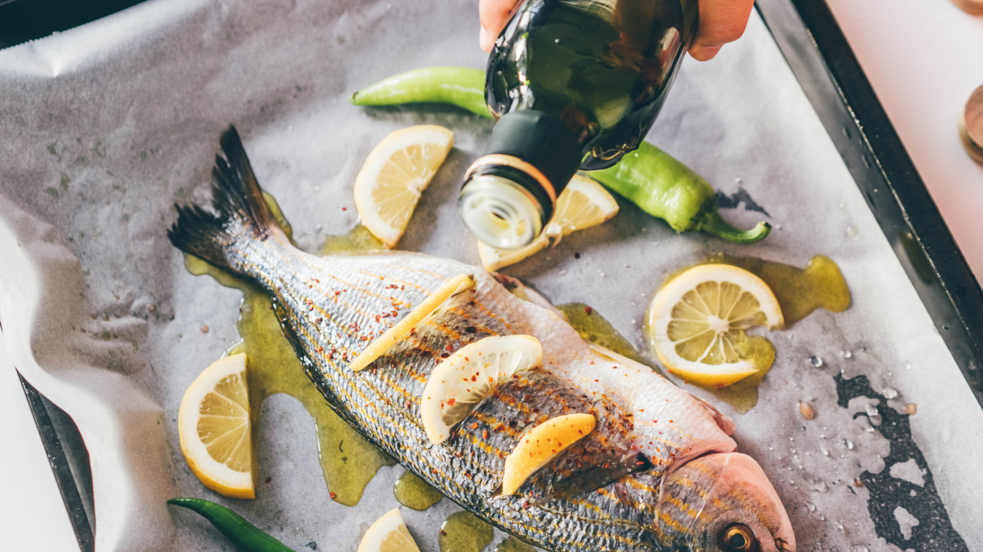 Fisch mit Zitrone und Olivenöl auf Backblech zubereiten.