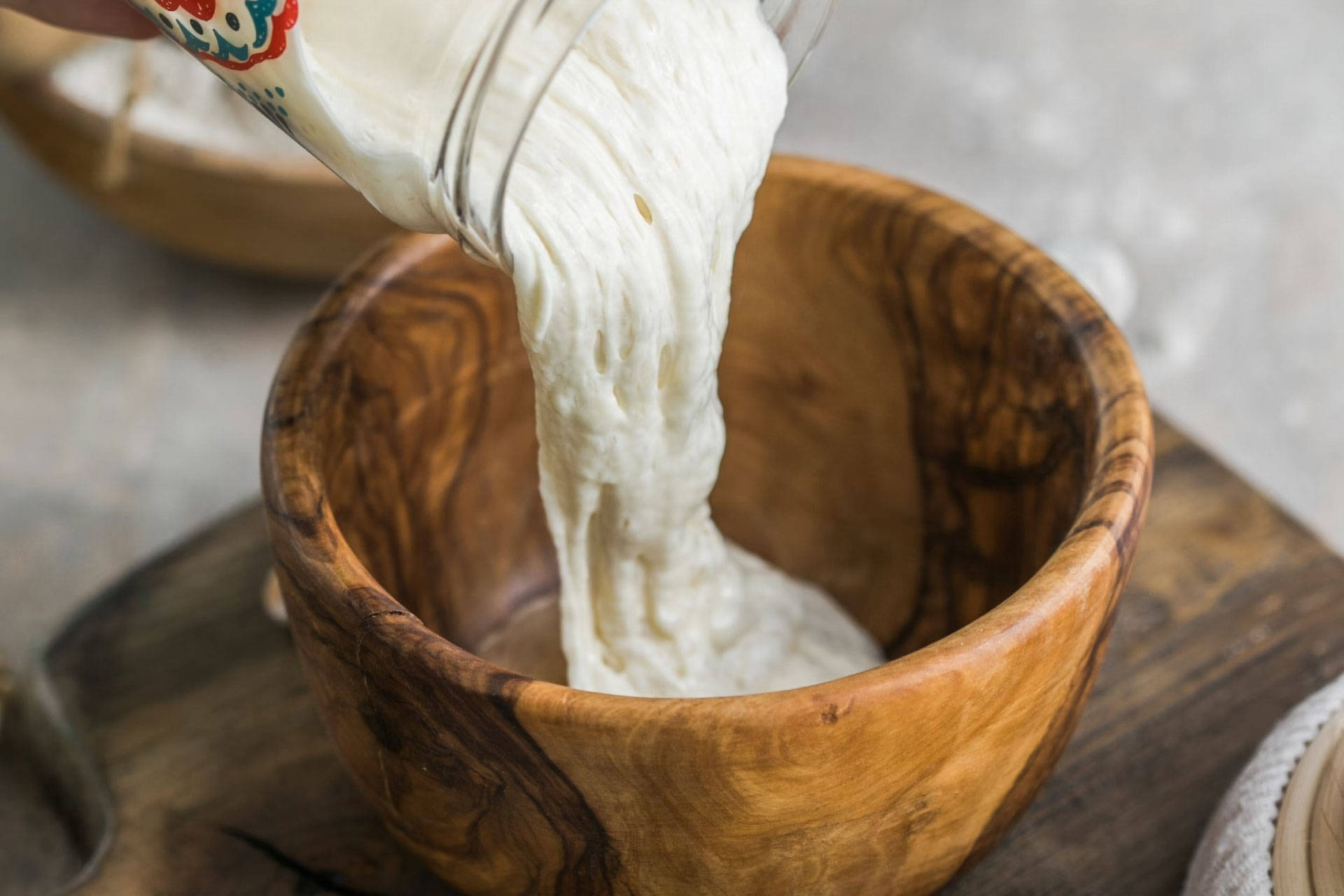 Sauerteig-Starter wird in Holzschüssel gegossen.