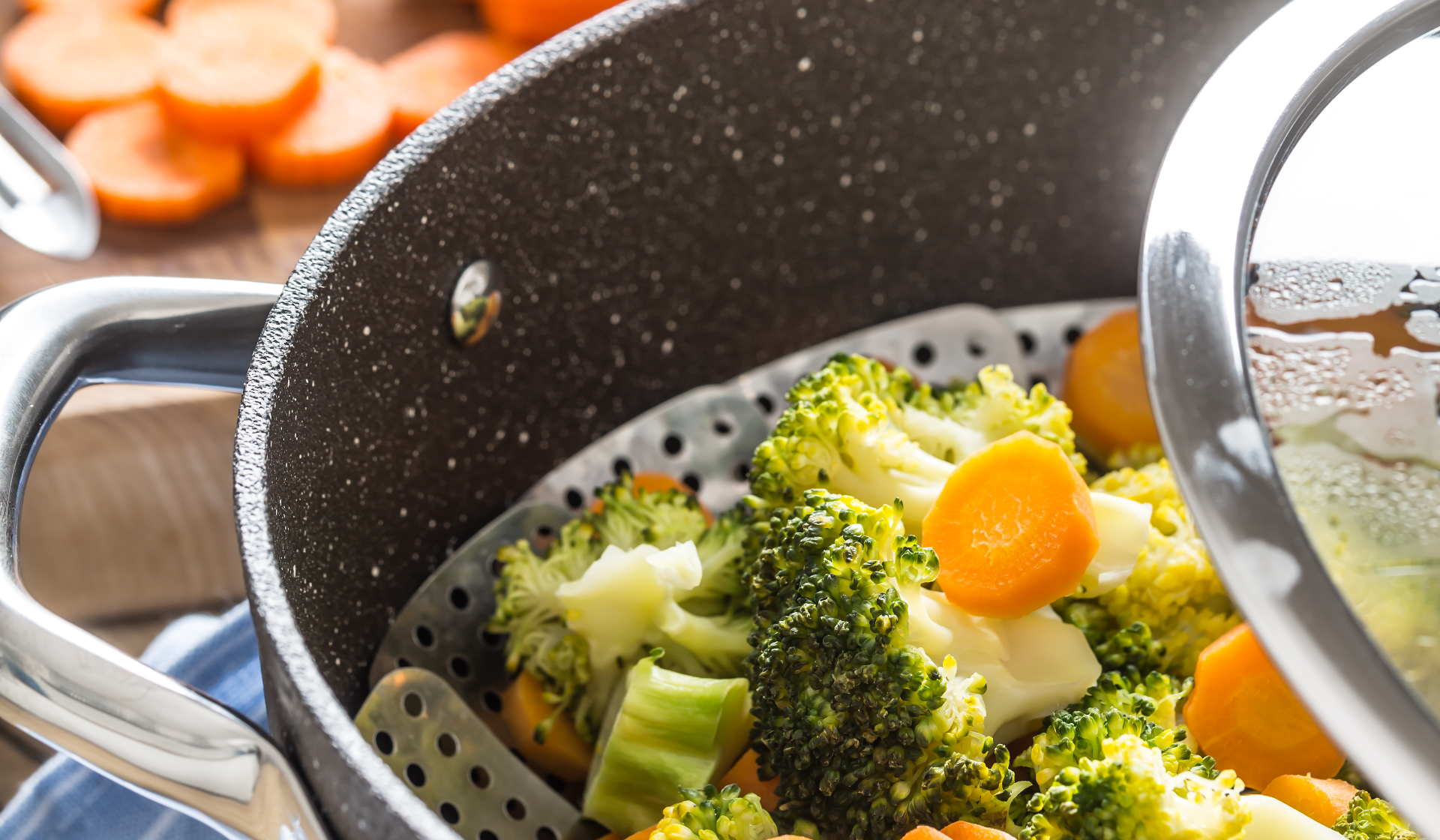 Ein Kochtopf mit Gareinsatz und Brokkoli, sowie Karotten.