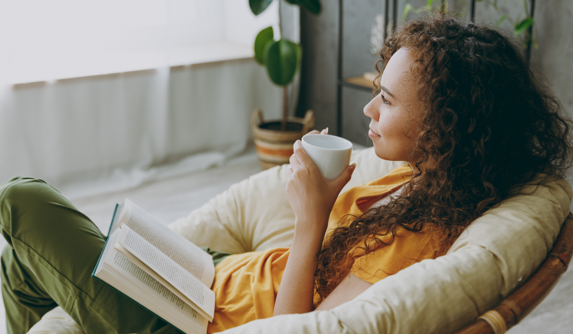 Eine Frau entspannt sich mit einer Tasse Tee in einem Sessel.