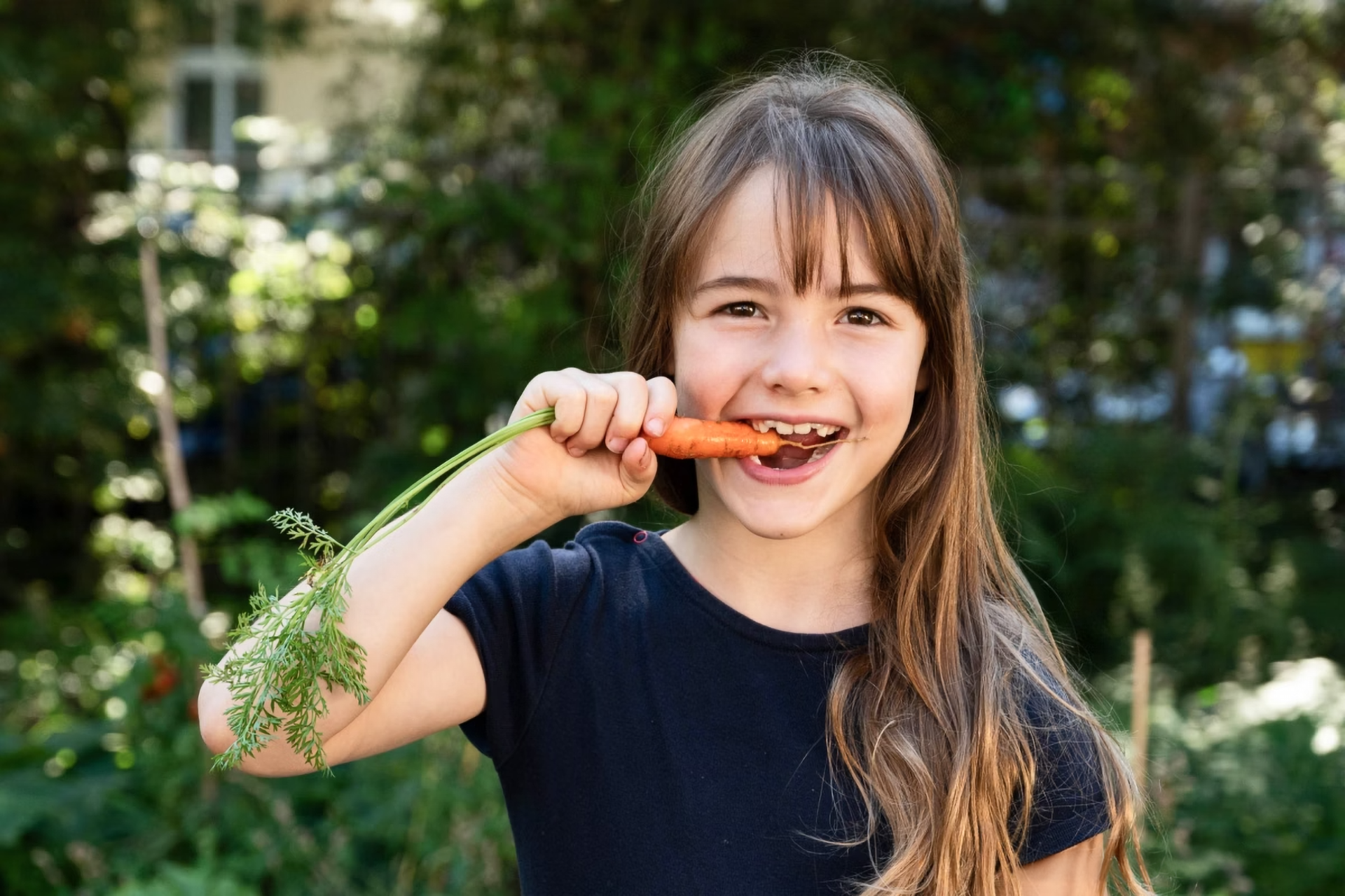 Ein Kind beißt in eine firsch geerntete Möhre.