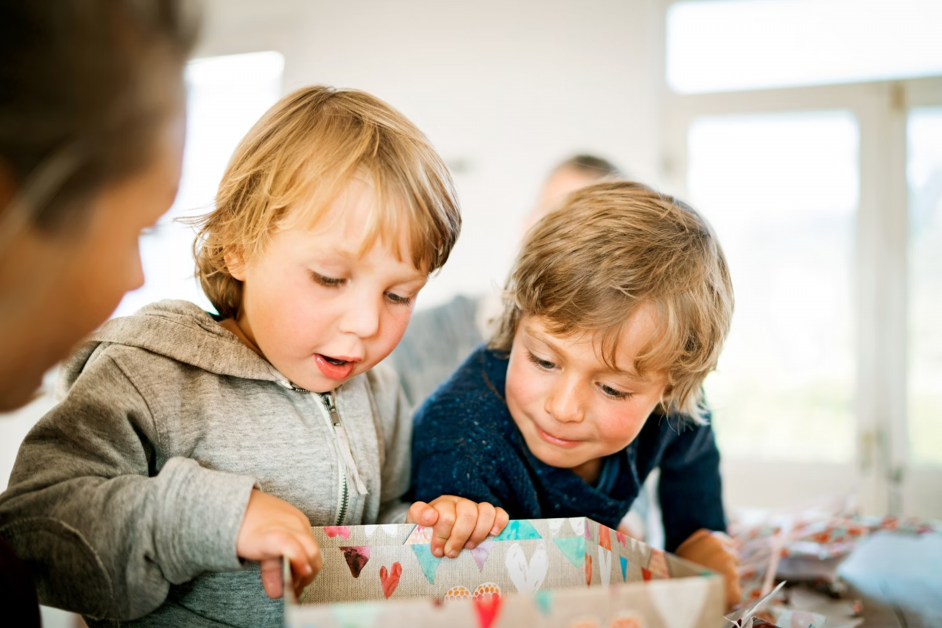 Zwei kleine Kinder halten eine Geschenbox und schauen hinein.