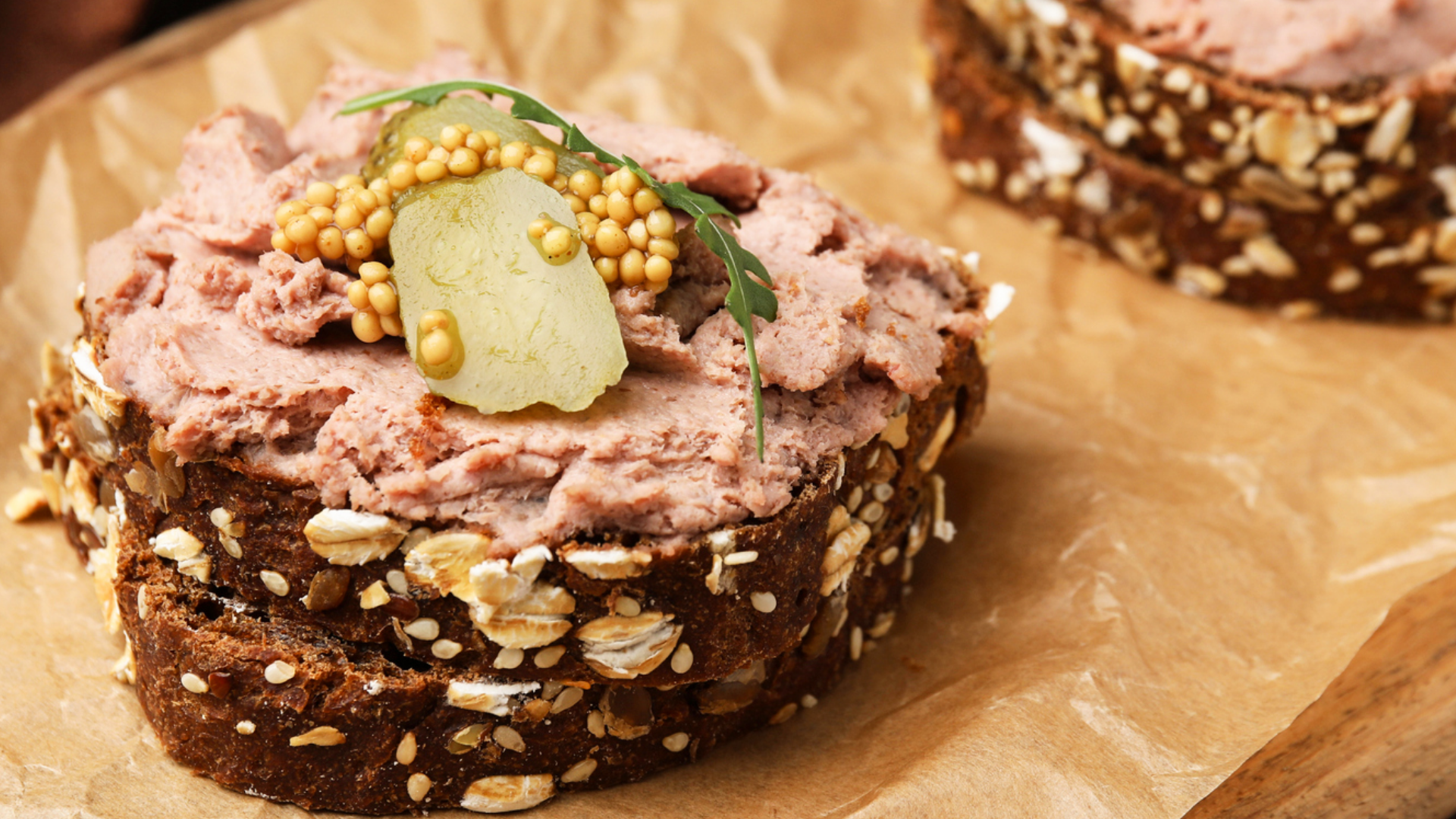 Vollkornbrot mit Streichwurst, Gewürzgurke, Körnersenf und Rucola.
