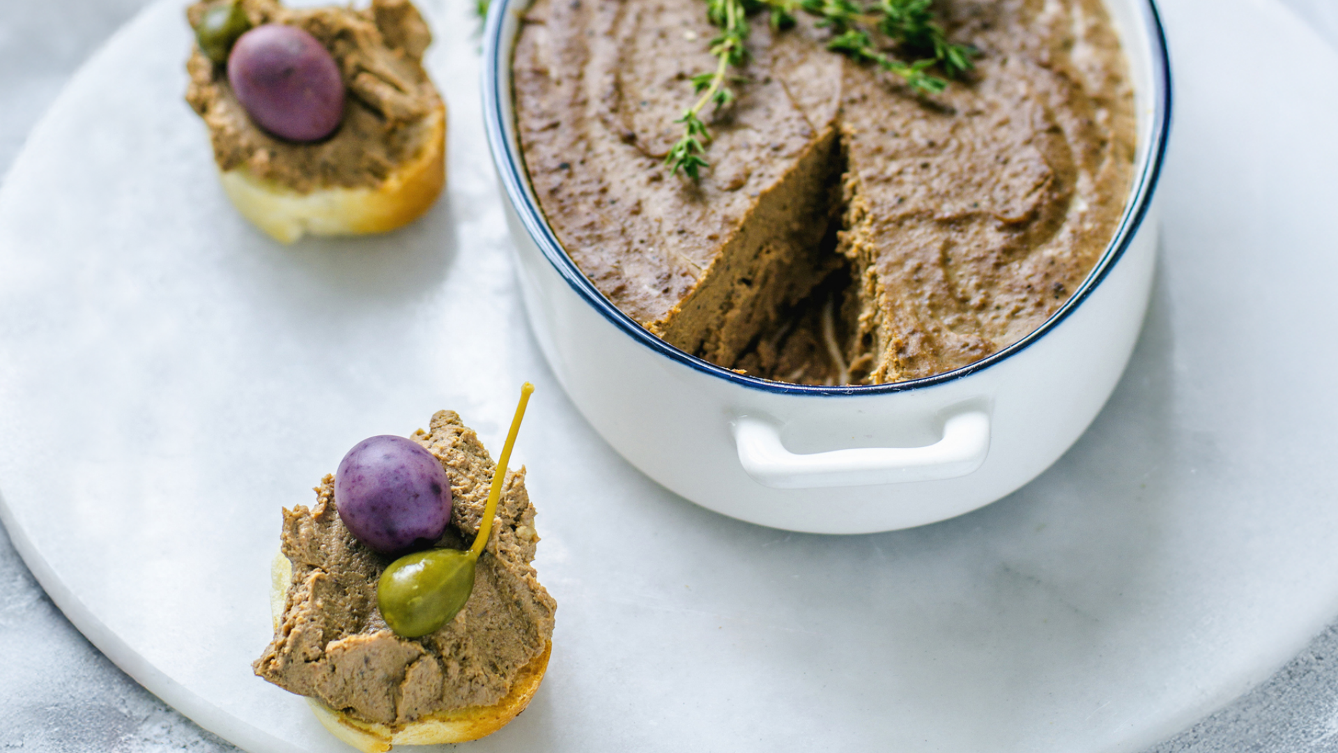 Streichwurst in Schale und auf Brot mit Weintrauben.
