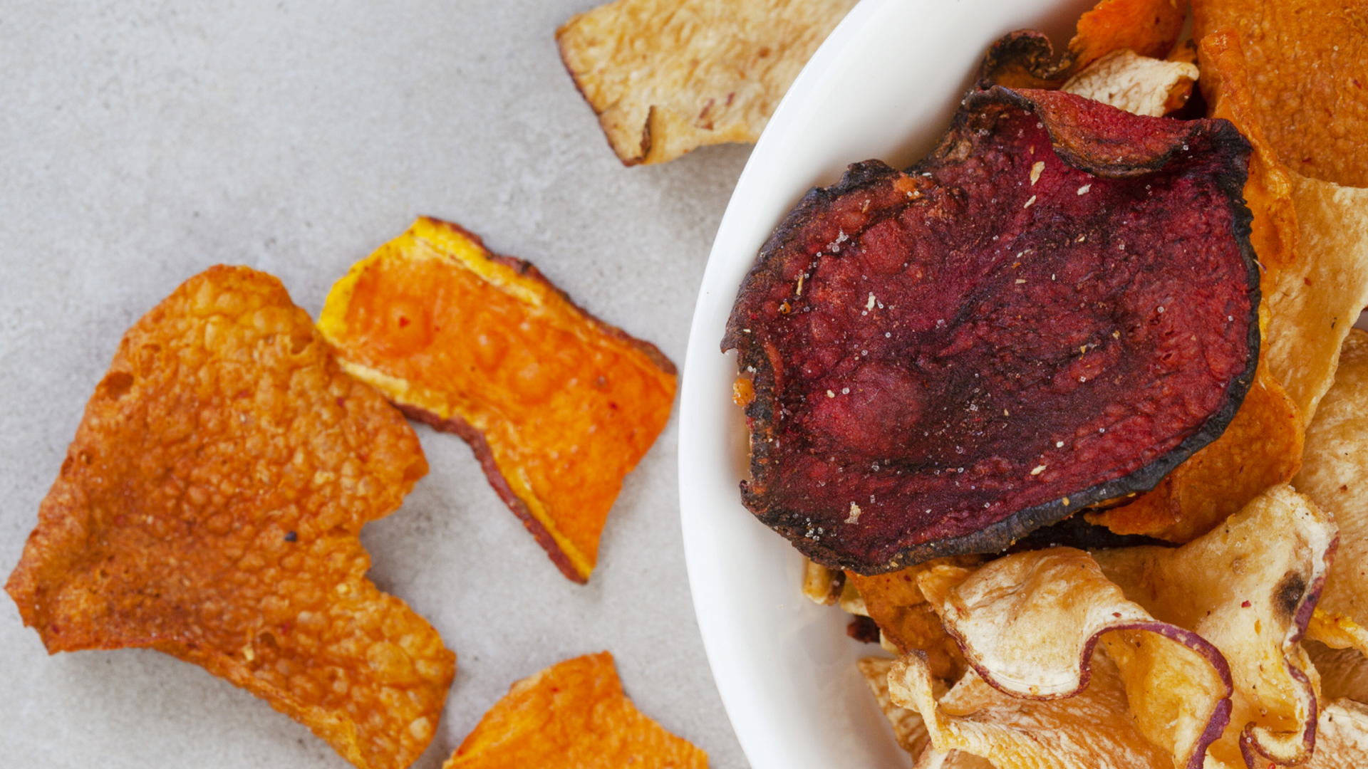 Gemüsechips in Schale und auf Untergrund, Nahaufnahme.