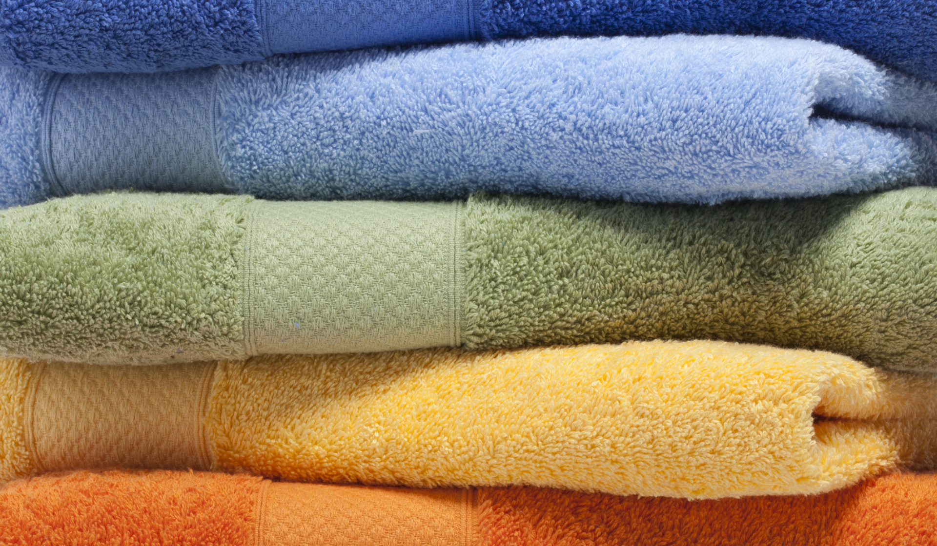 Bunter Stapel gefalteter Frottee-Handtücher in verschiedenen Farben.