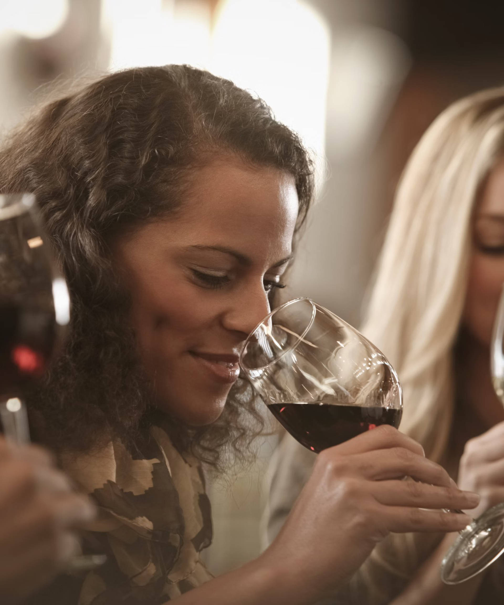 Frauen bei einer Weinprobe, eine trinkt Rotwein, die andere Weißwein.