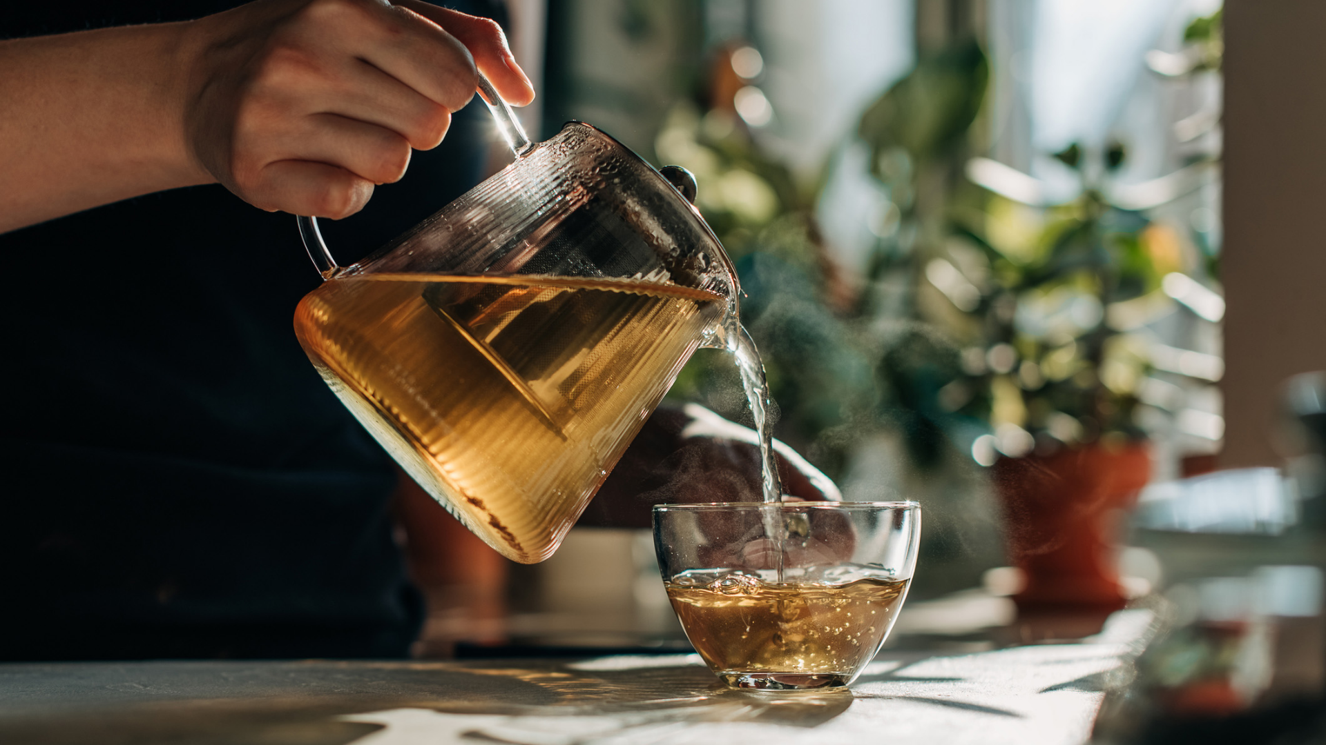 Tee wird aus Glaskanne in Glas gegossen.