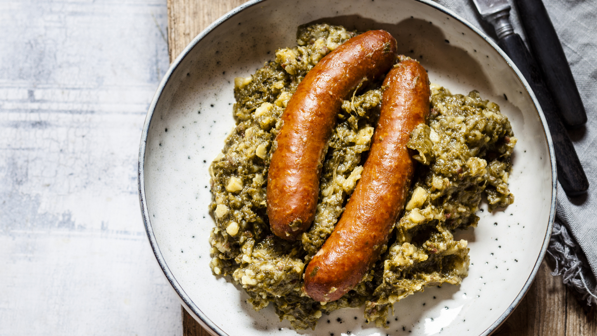 Grünkohl mit Würstchen in einem Teller, rustikale Präsentation.