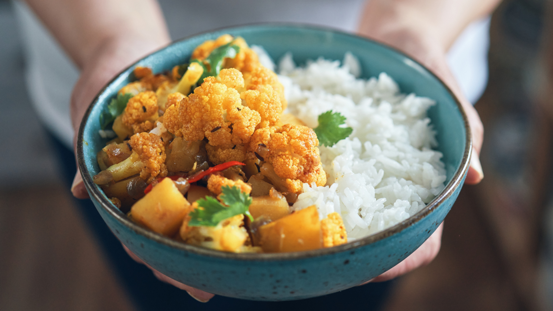 Person hält Schüssel mit Curry und Reis.