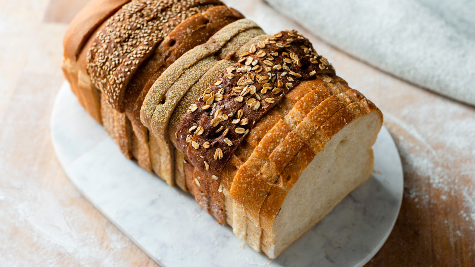Aufgeschnittenes Mehrkornbrot auf heller Marmorplatte.