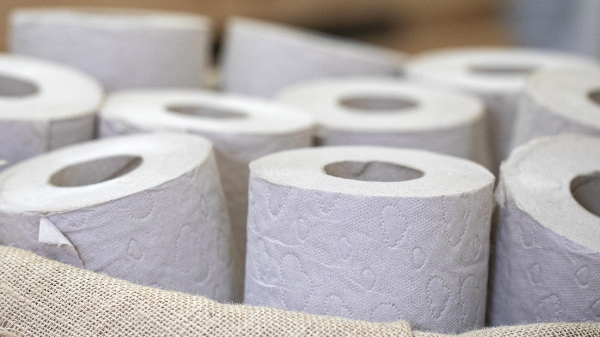 Weiße Toilettenpapierrollen mit Prägung in Stoffkorb.