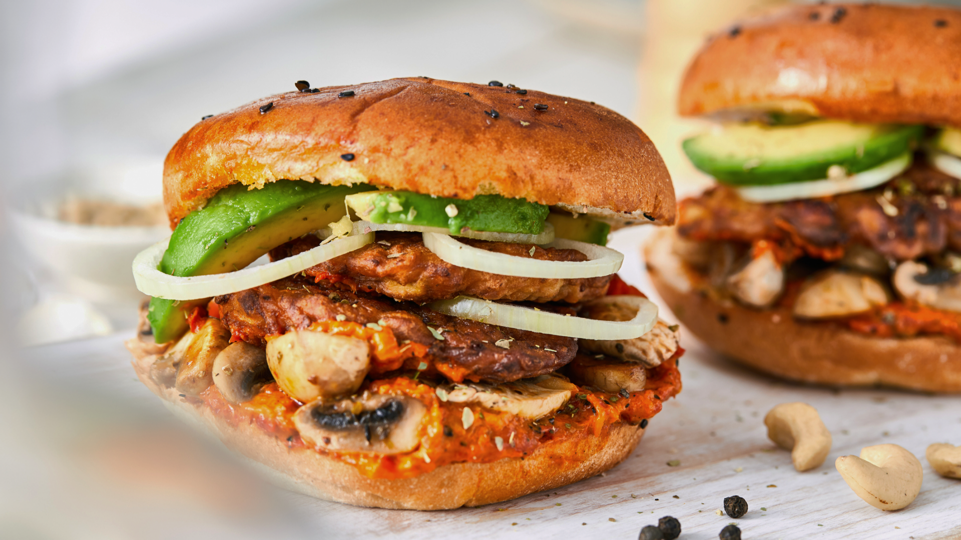 Zwei vegane Burger mit Avocado, Pilzen und Zwiebeln.