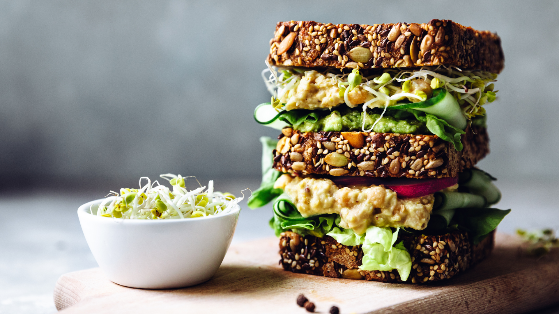 Mehrlagiges Körnerbrot-Sandwich mit veganem Aufstrich und Gemüse.