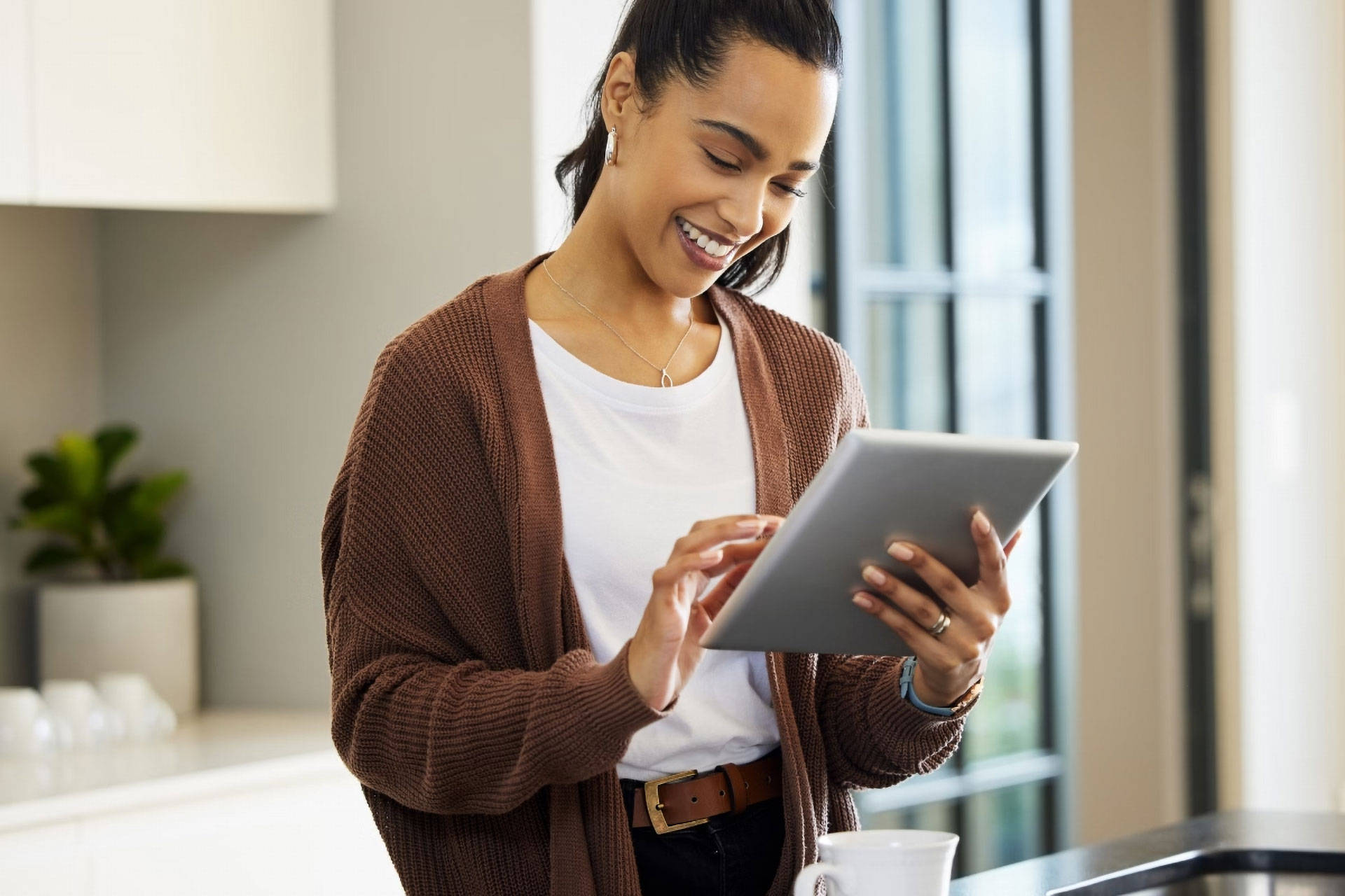 Frau bedient ein Tablet und lächelt dabei.