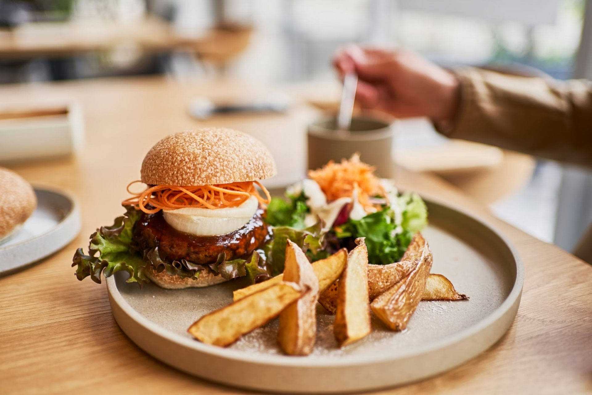Ein angerichteter Teller mit einem veganem Burger und Kartoffelwedges.
