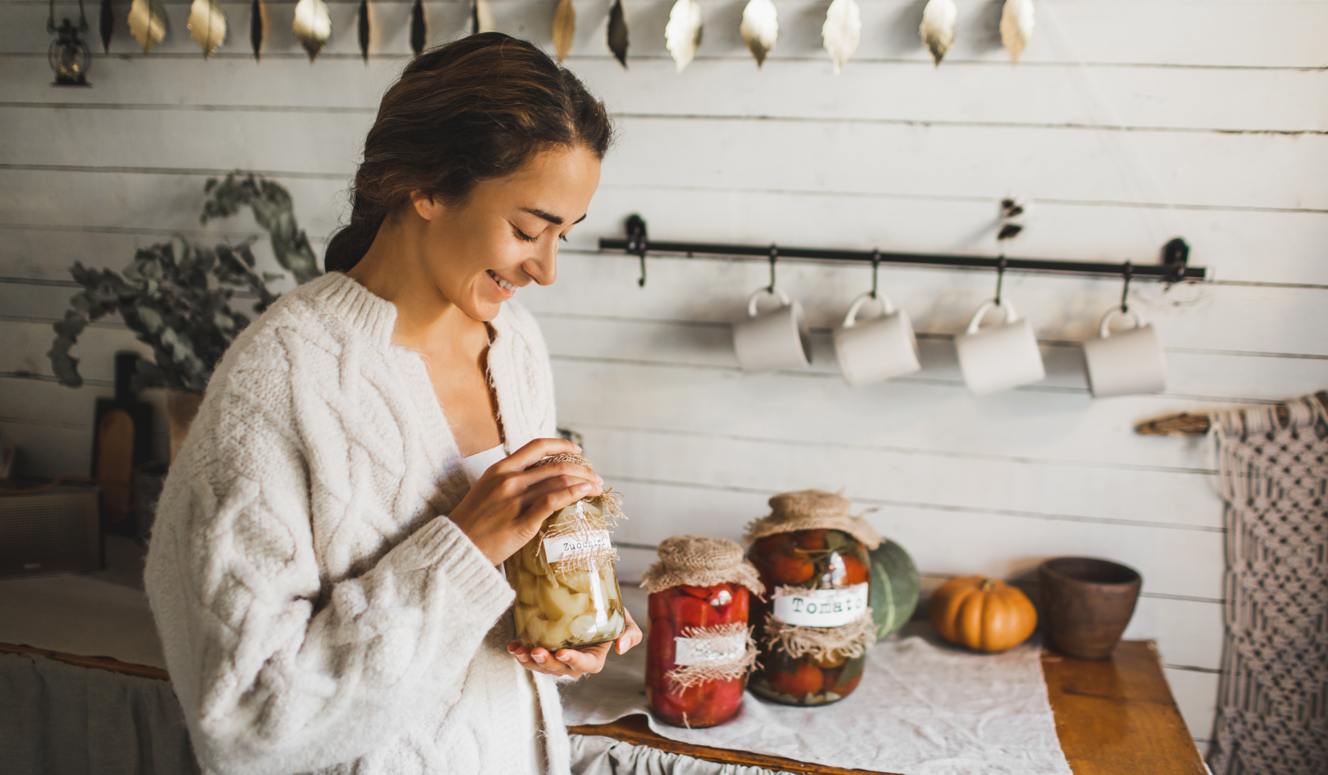 Eine junge Frau mit drei Gläsern eingelegter Lebensmittel.