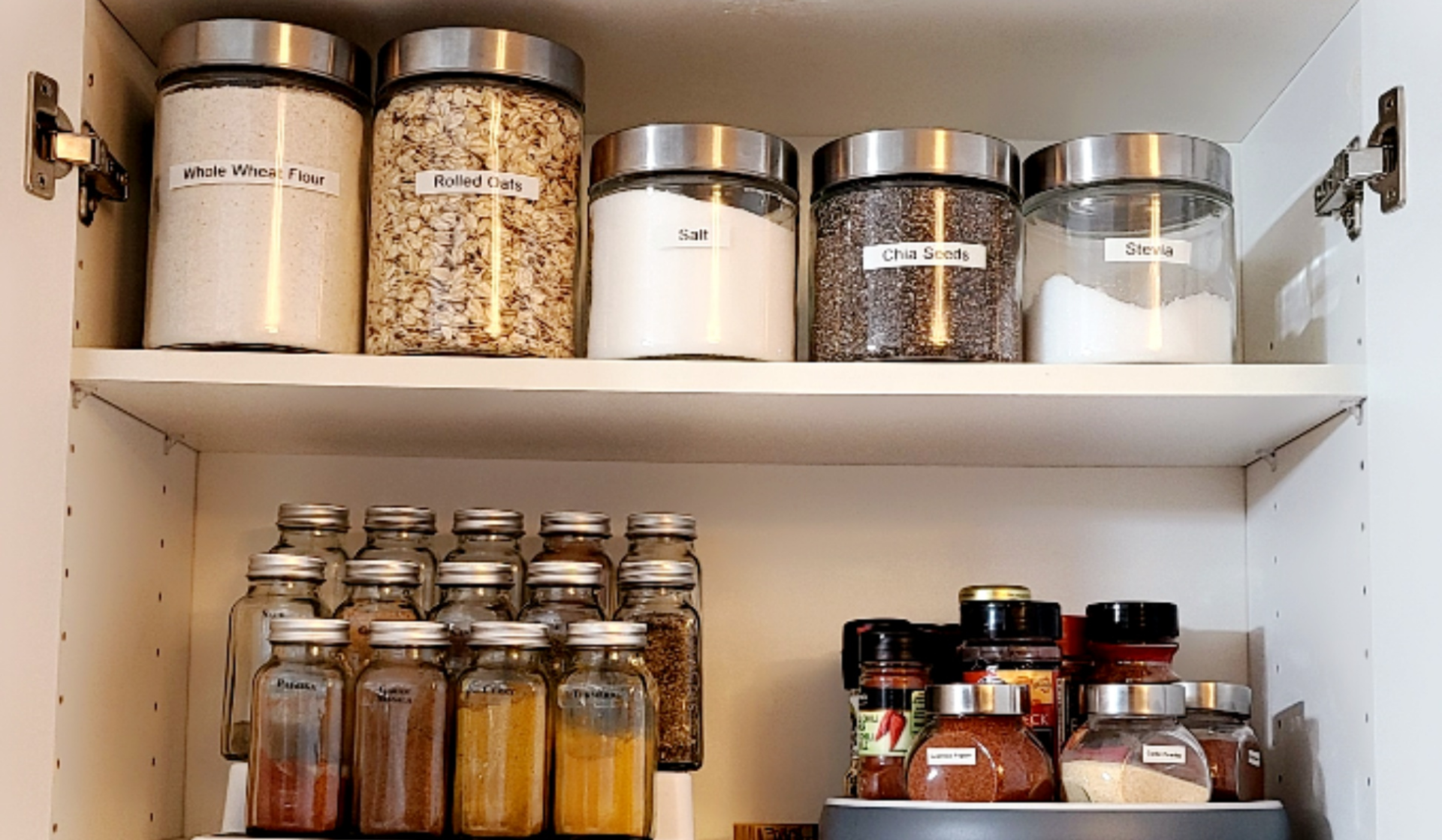 Ein Vorratsschrank mit trockenen Lebensmitteln und Gewürzen in Gläsern.