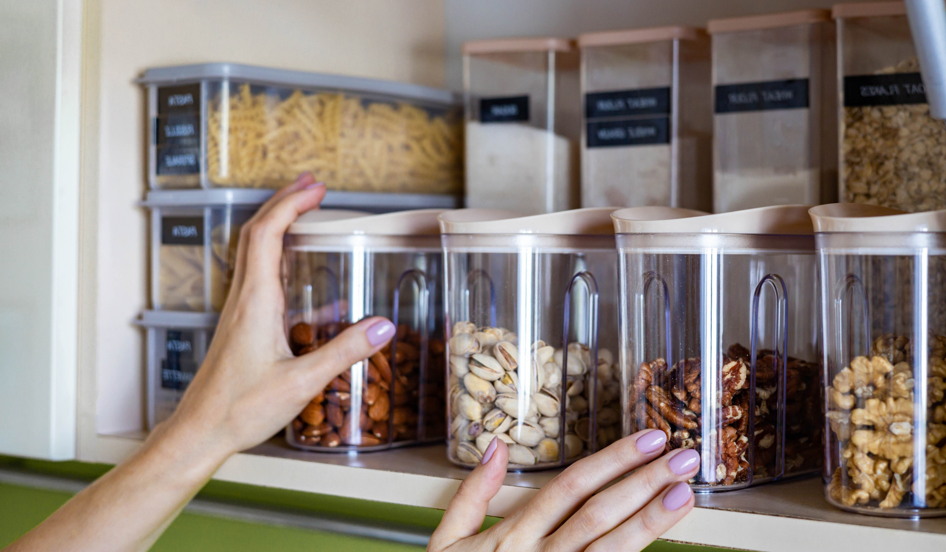 Hände greifen nach einem Vorratsbehälter mit Nüssen.