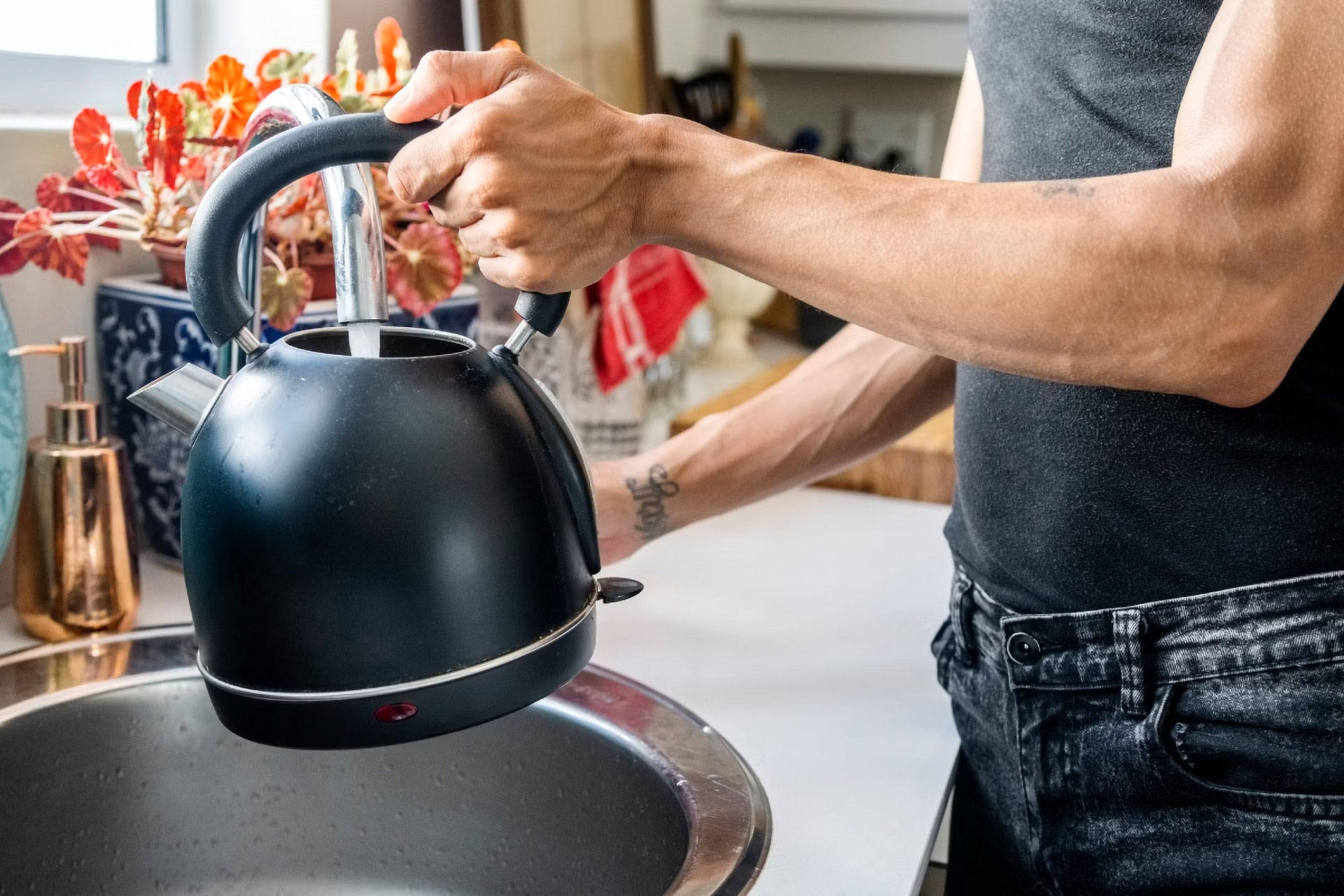 Eine Person füllt Ihren Wasserkocher am Waschbecken.