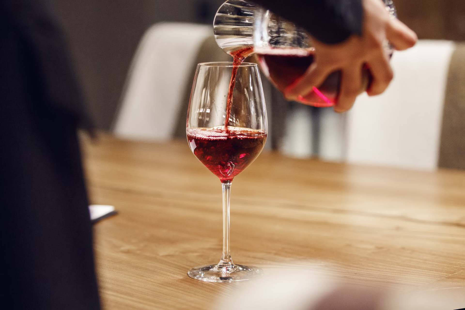 Rotwein wird aus einer Karaffe in ein Weinglas gegossen, um den Wein zu dekantieren.
