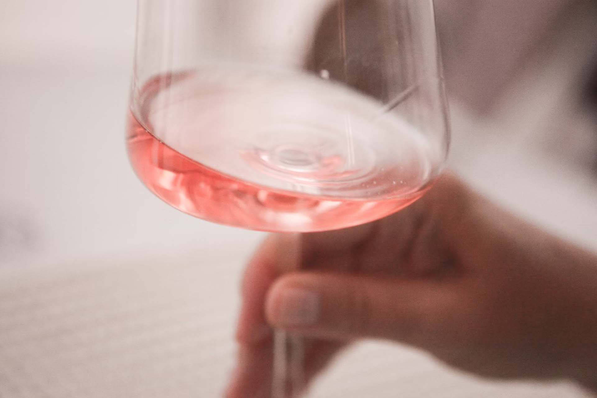 Nahaufnahme eines Weinglases mit blassrosa Wein.