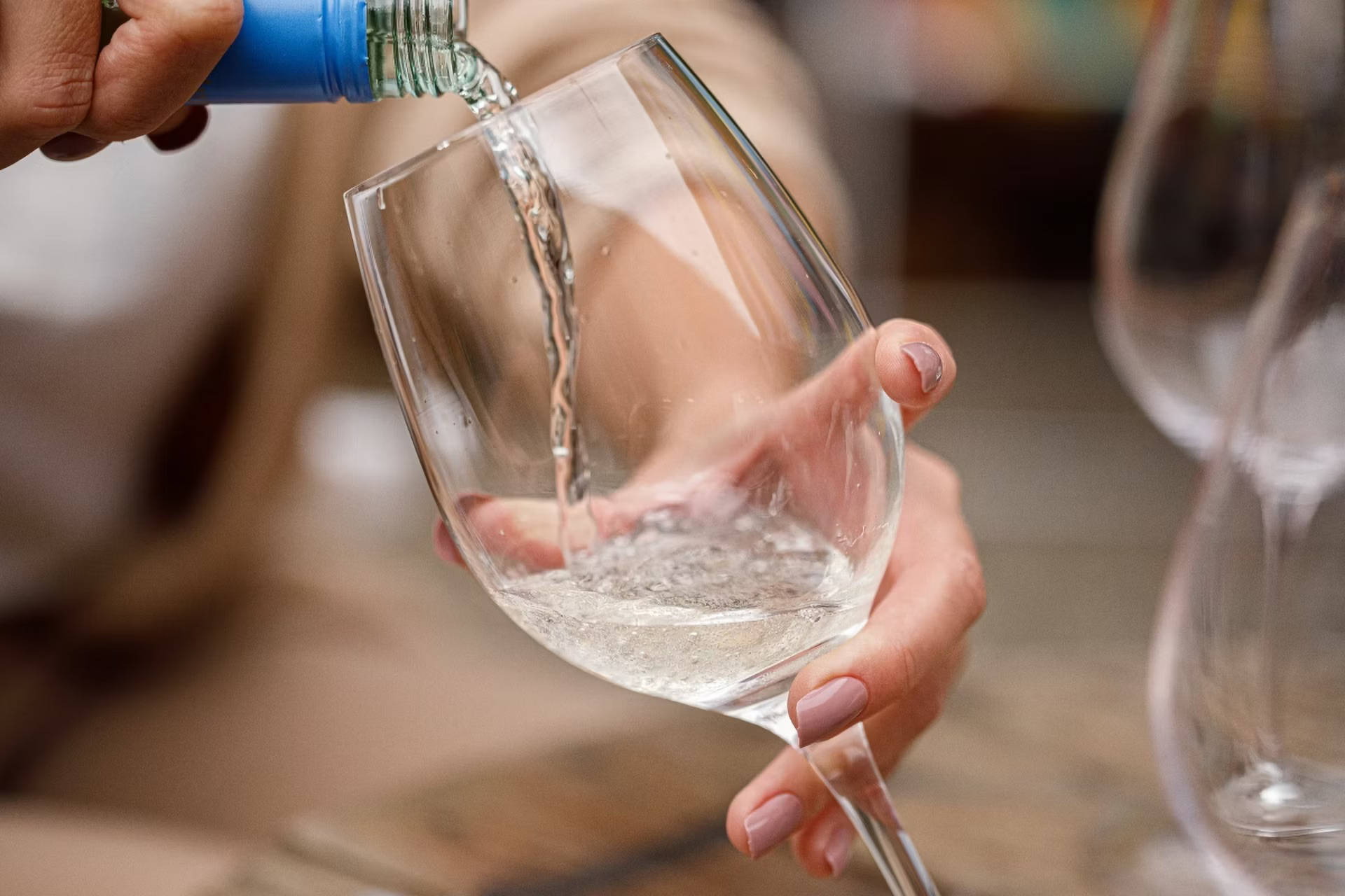 Jemand schenkt sich Weißwein ins Glas.