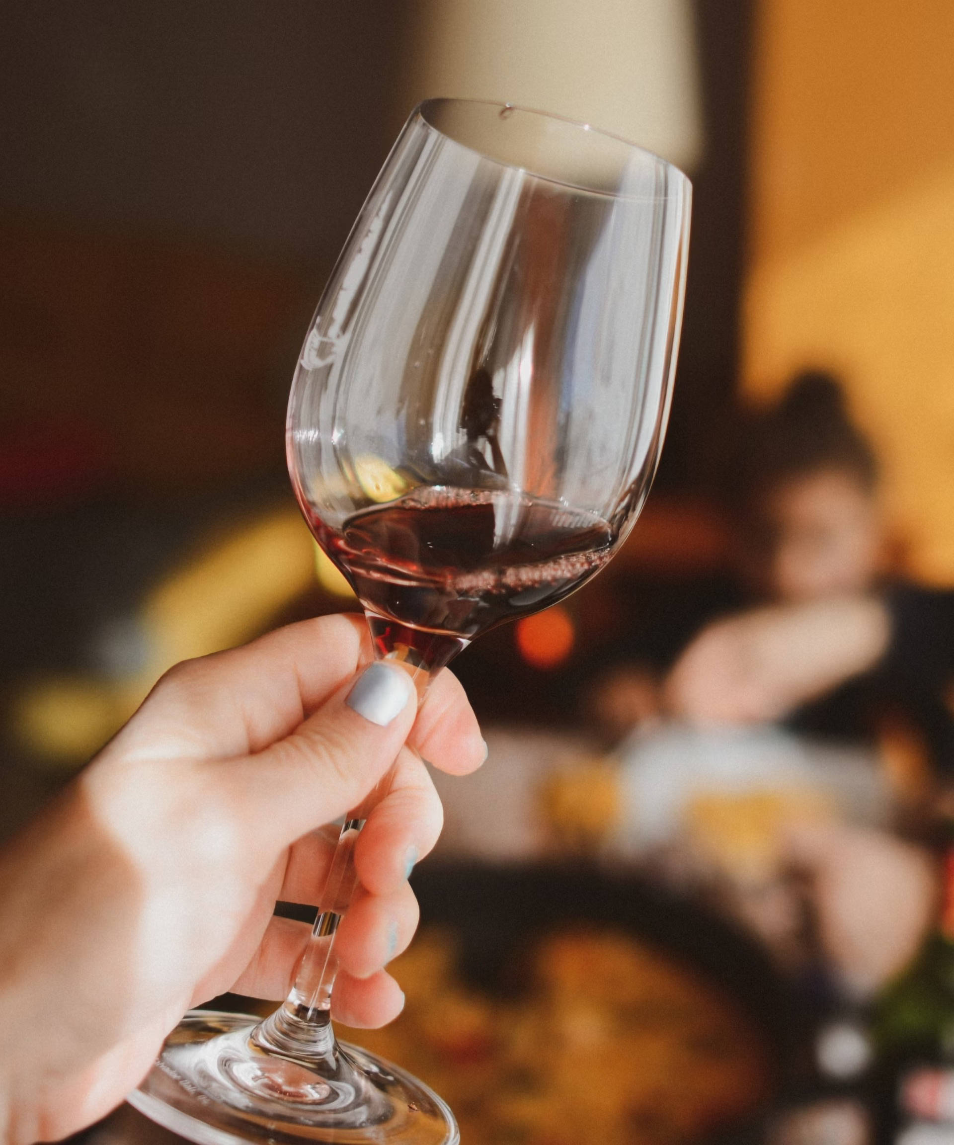 Eine Person hält ein Rotweinglas gekippt zur Seite, um zu prüfen ob er korkt.