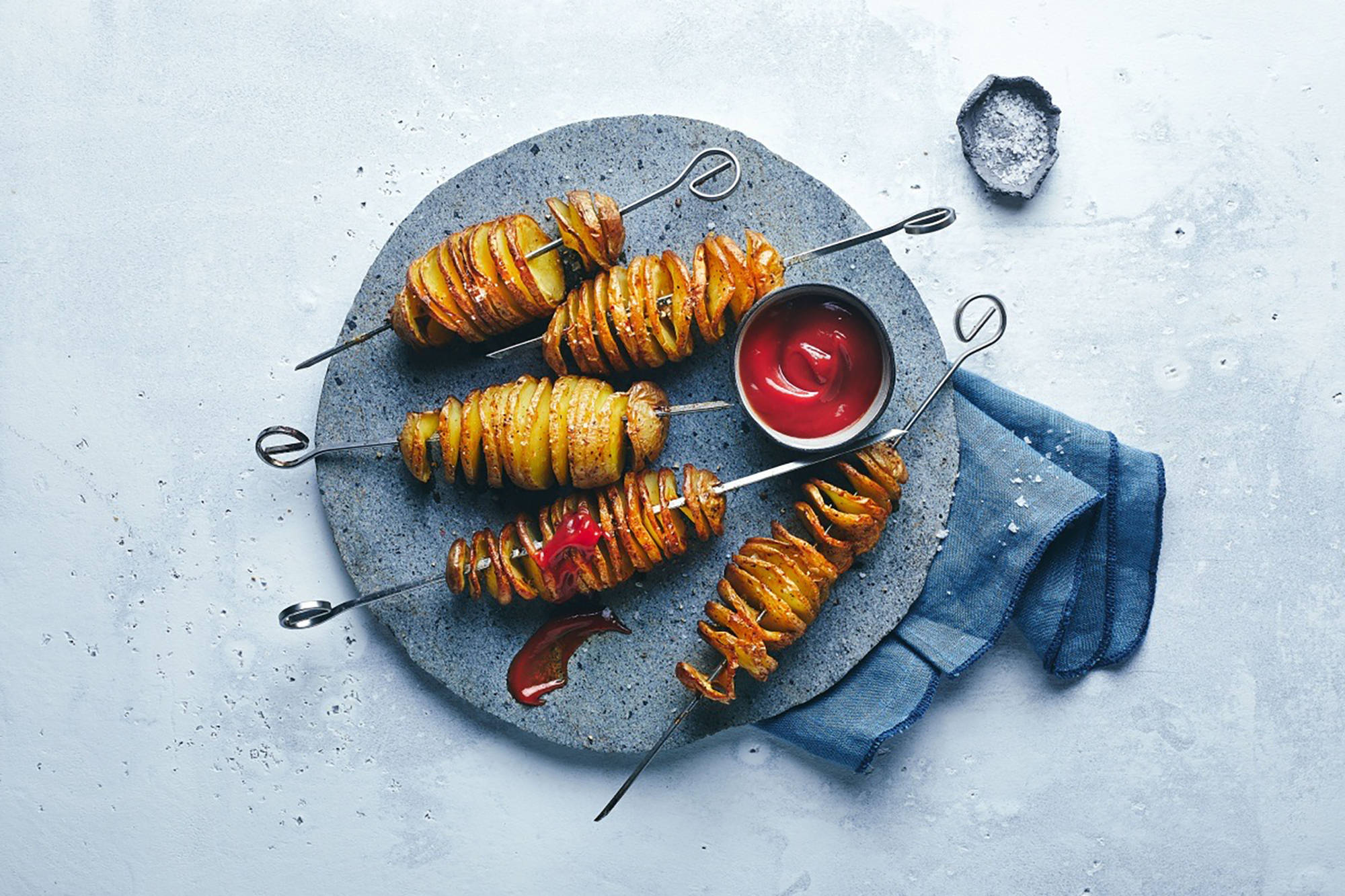 Spiralkartoffelspieße serviert mit Ketchup auf einem grauen Teller.
