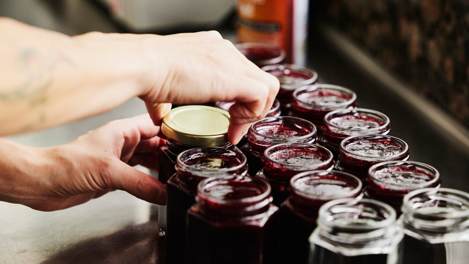 Hände verschließen Gläser mit roter Marmelade/Konfitüre.
