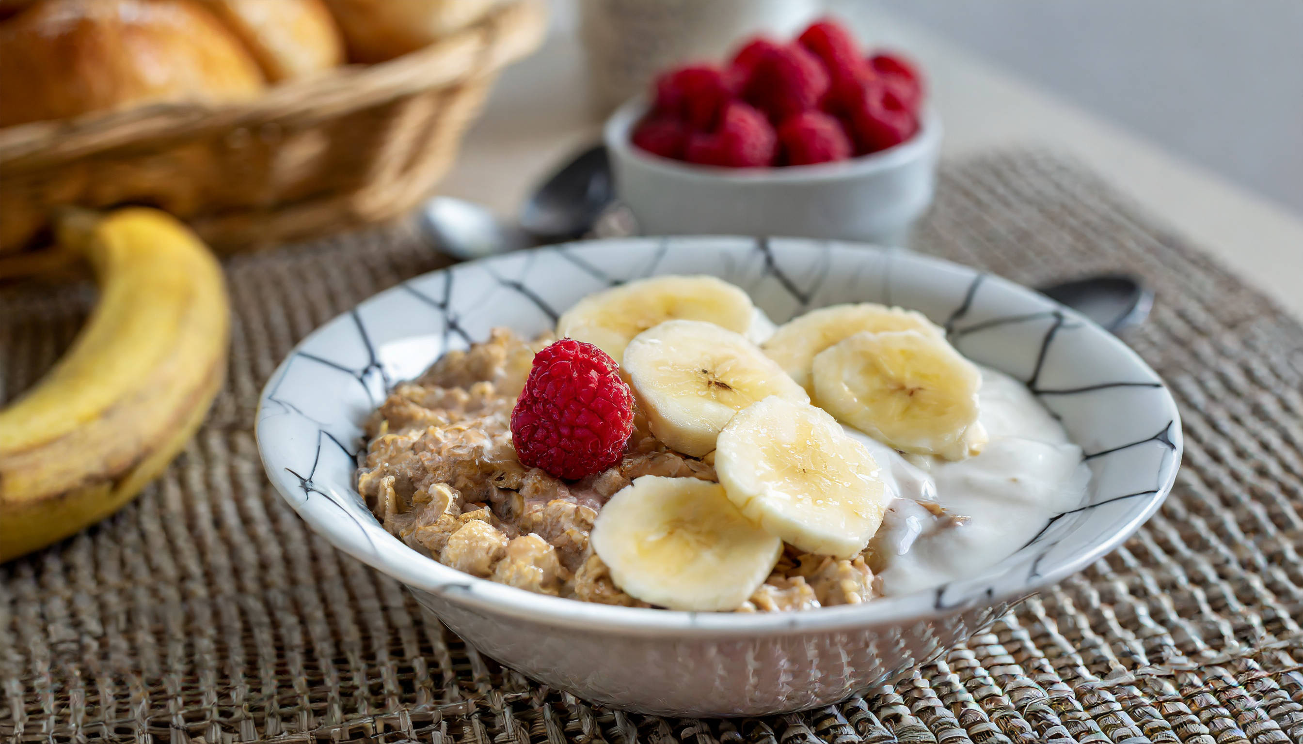 Schale mit Haferbrei, Bananen, Himbeere und Joghurt.