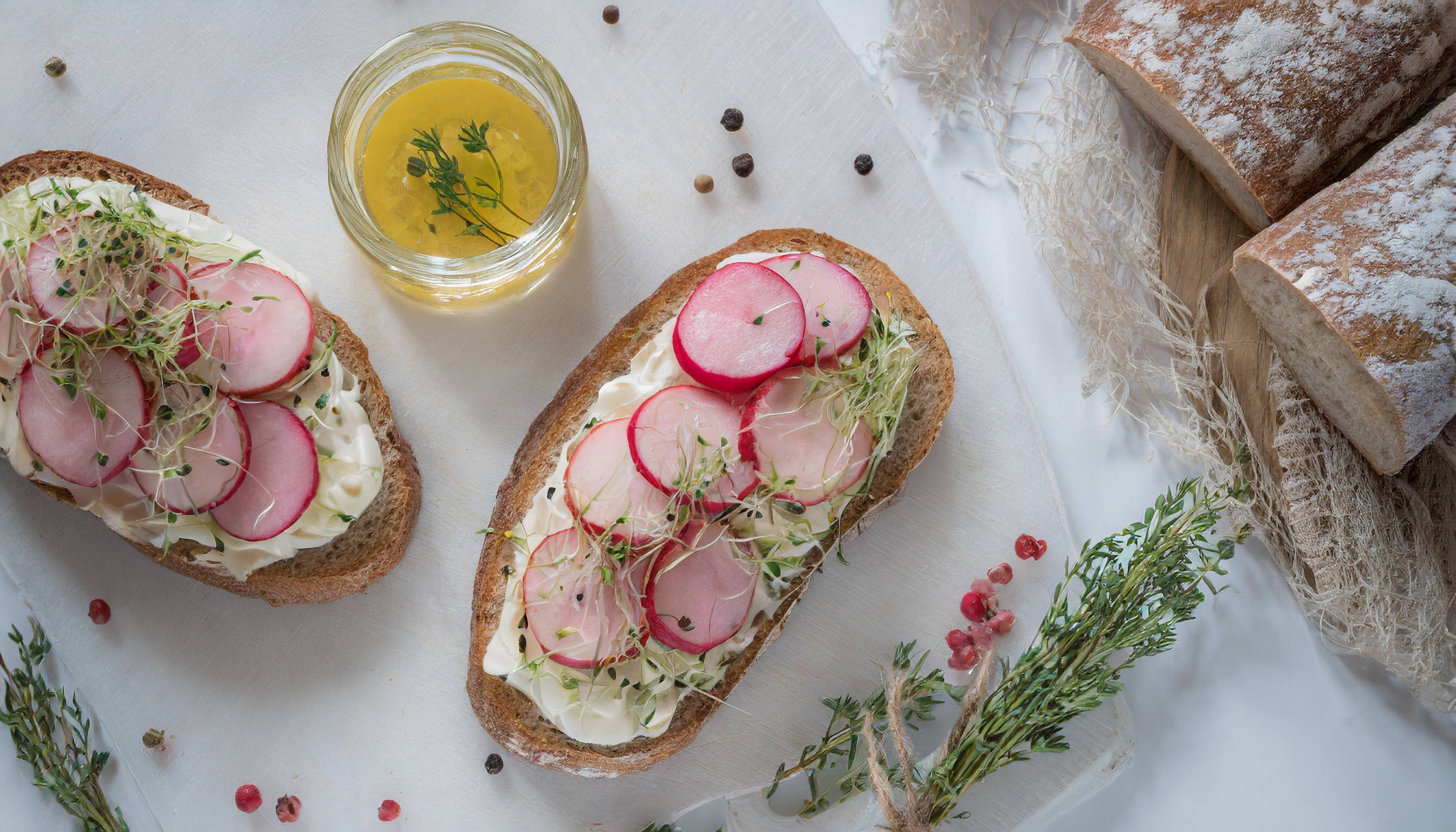 Belegte Brote mit Radieschen, Sprossen, Kräutern und Öl.