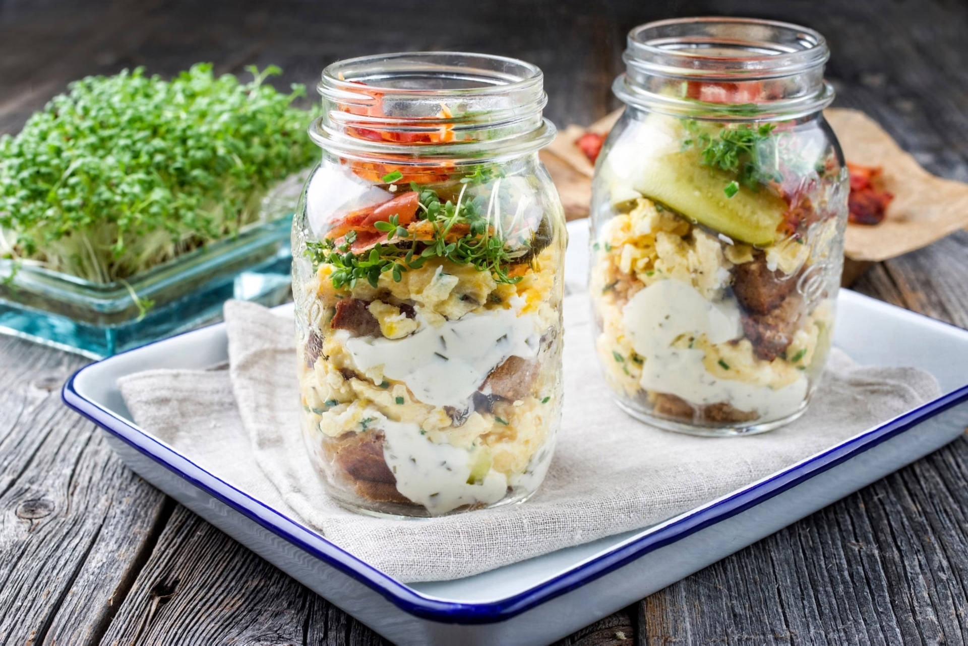 Geschichtetes Rührei mit Speck und Kräutern in Gläsern.