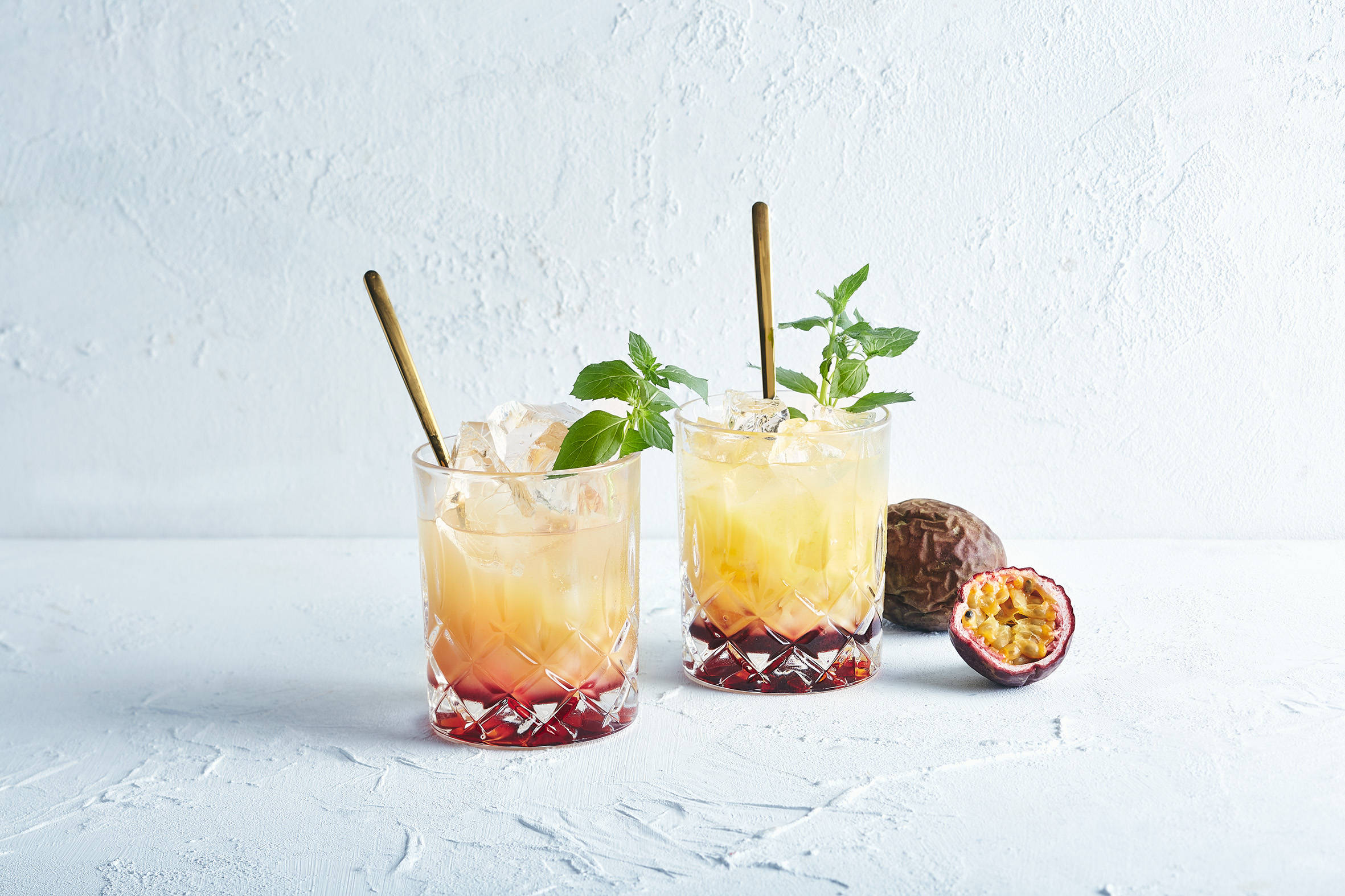 Zwei Cocktails mit Eis und Maracuja.
